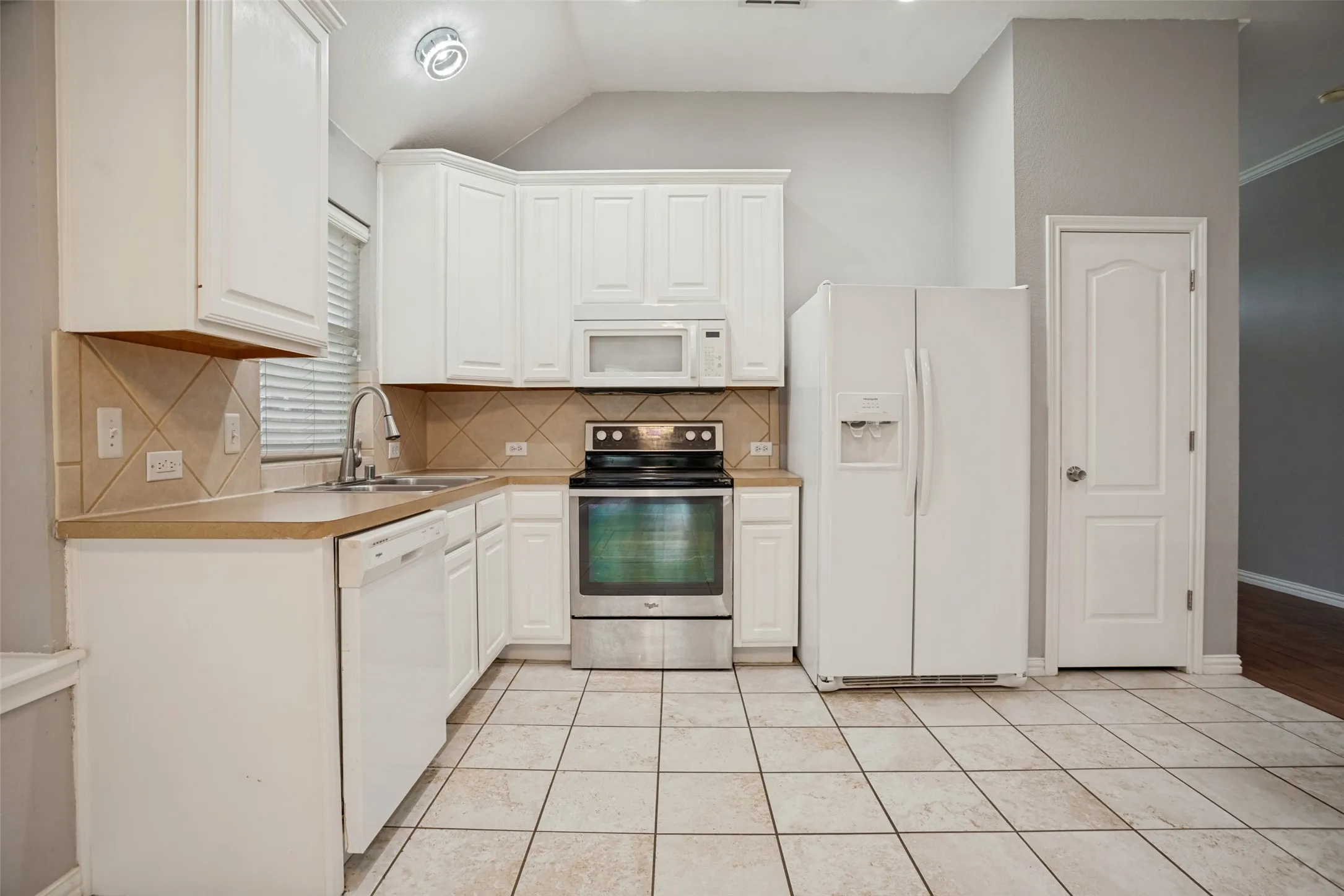 Kitchen featuring white cabinetry, a tiled backsplash, and light-toned countertops