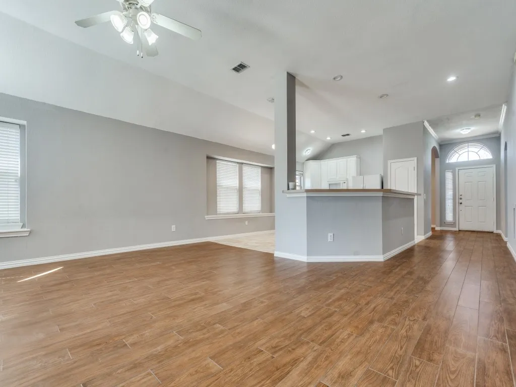 Unfurnished living room featuring a wealth of natural light, visible vents, vaulted ceiling, and light wood finished floors
