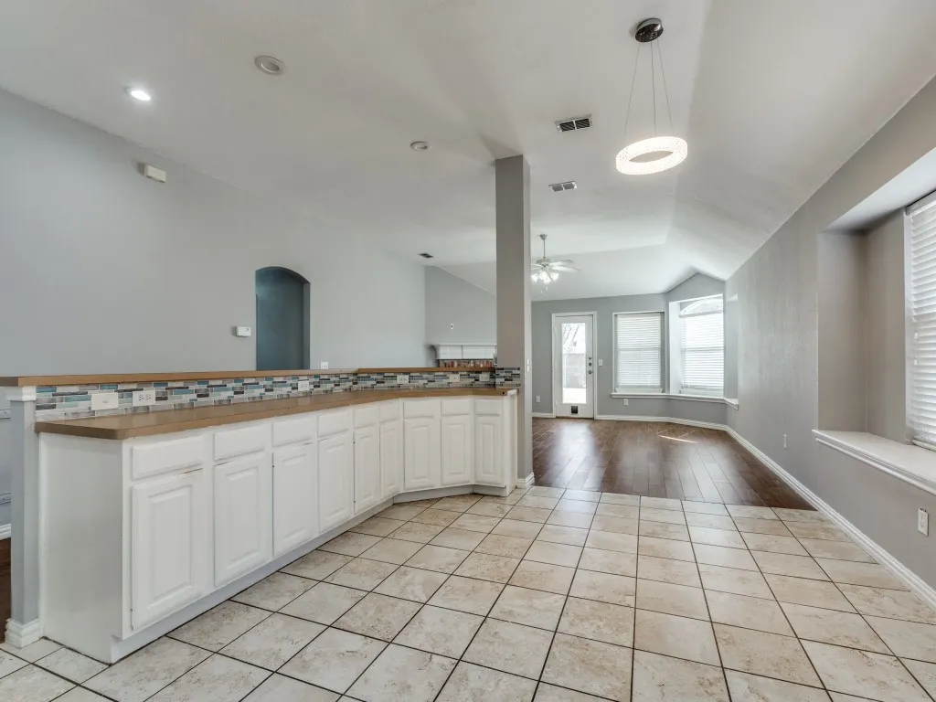 Kitchen with a ceiling fan, visible vents, lofted ceiling, white cabinetry, and open floor plan