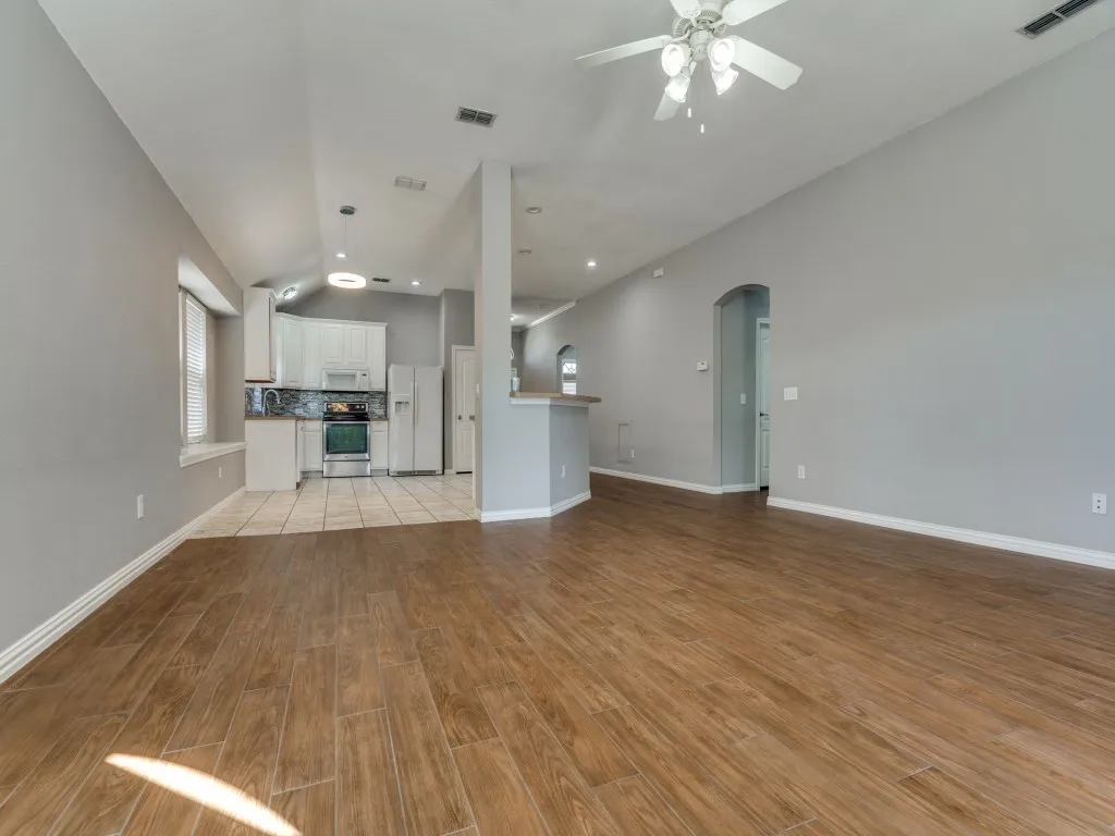 Unfurnished living room featuring visible vents, arched walkways, light wood-style flooring, and a ceiling fan