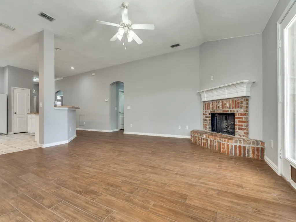 Unfurnished living room featuring visible vents, arched walkways, wood finished floors, and a fireplace