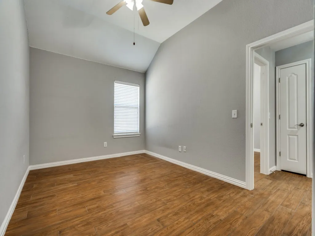 Unfurnished room with vaulted ceiling, a ceiling fan, baseboards, and wood finished floors