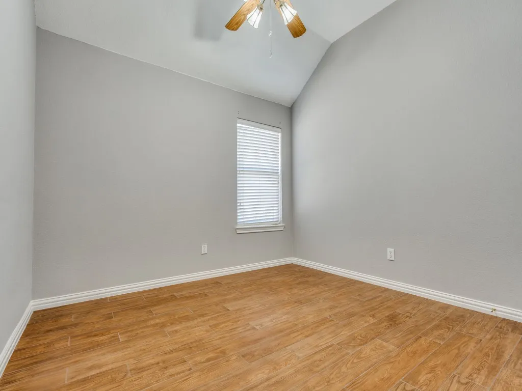 Spare room featuring light wood-style flooring, a ceiling fan, and lofted ceiling