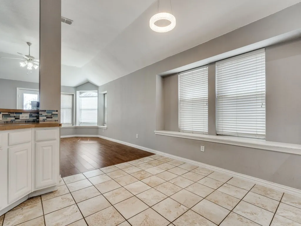 Kitchen featuring visible vents, vaulted ceiling, light tile patterned floors, white cabinets, and a ceiling fan