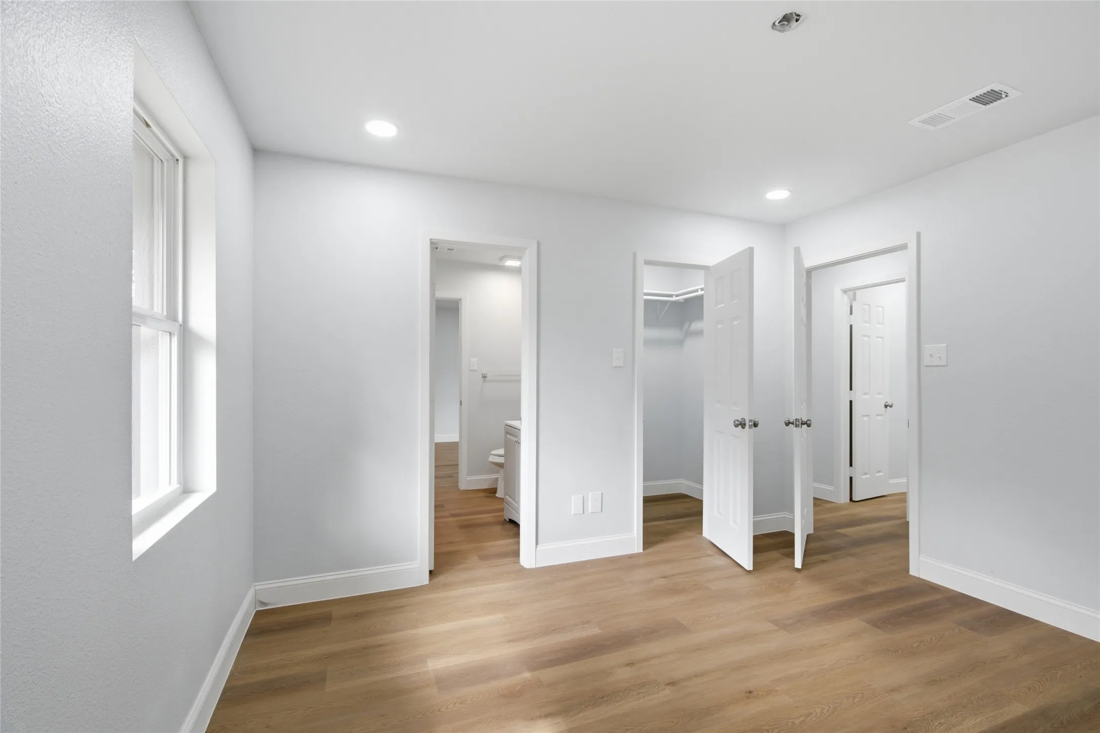 Spacious room with wood-finish flooring and white baseboards