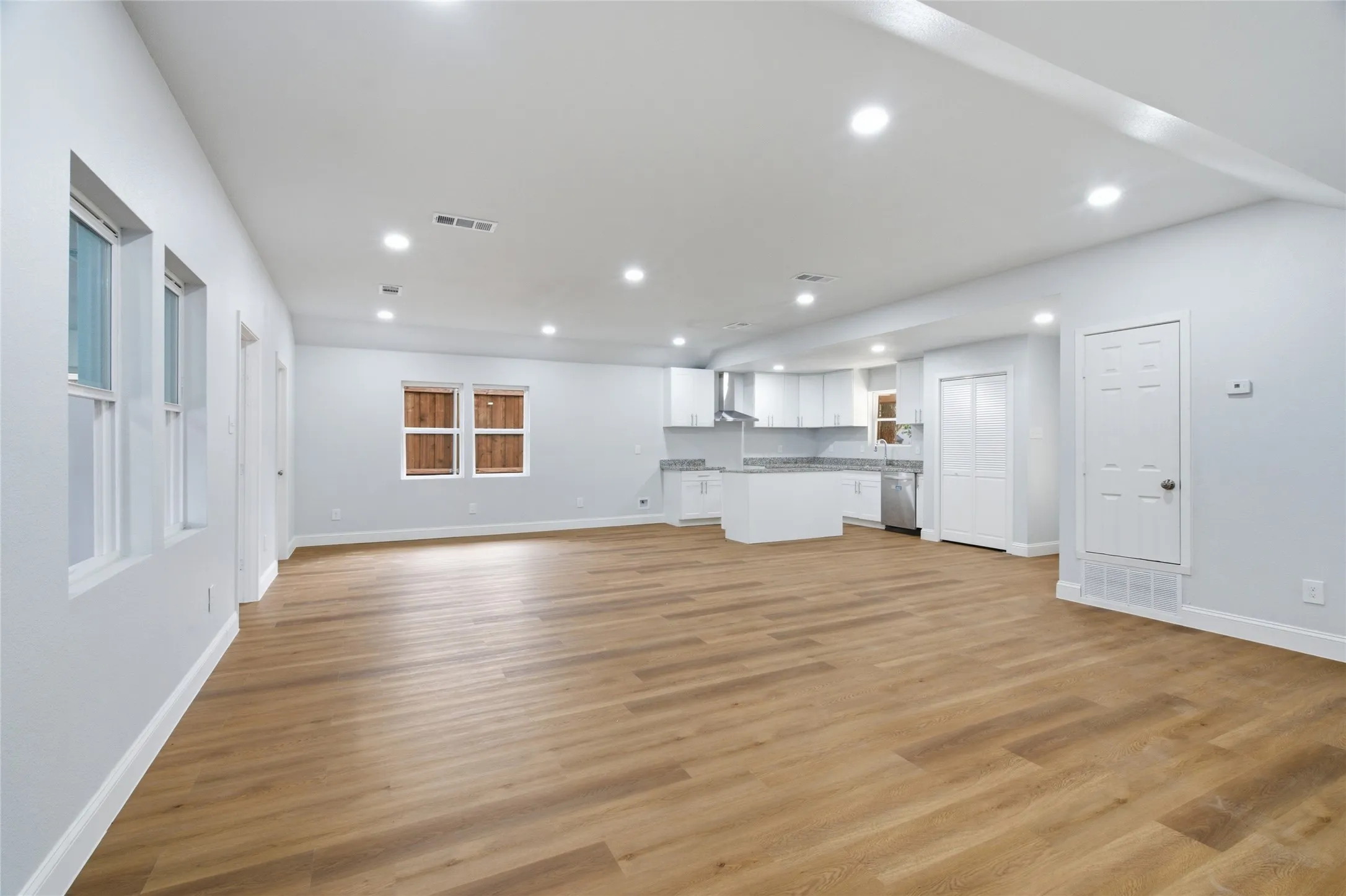 Open-concept living area featuring wood-finish flooring, recessed lighting, and light-toned walls