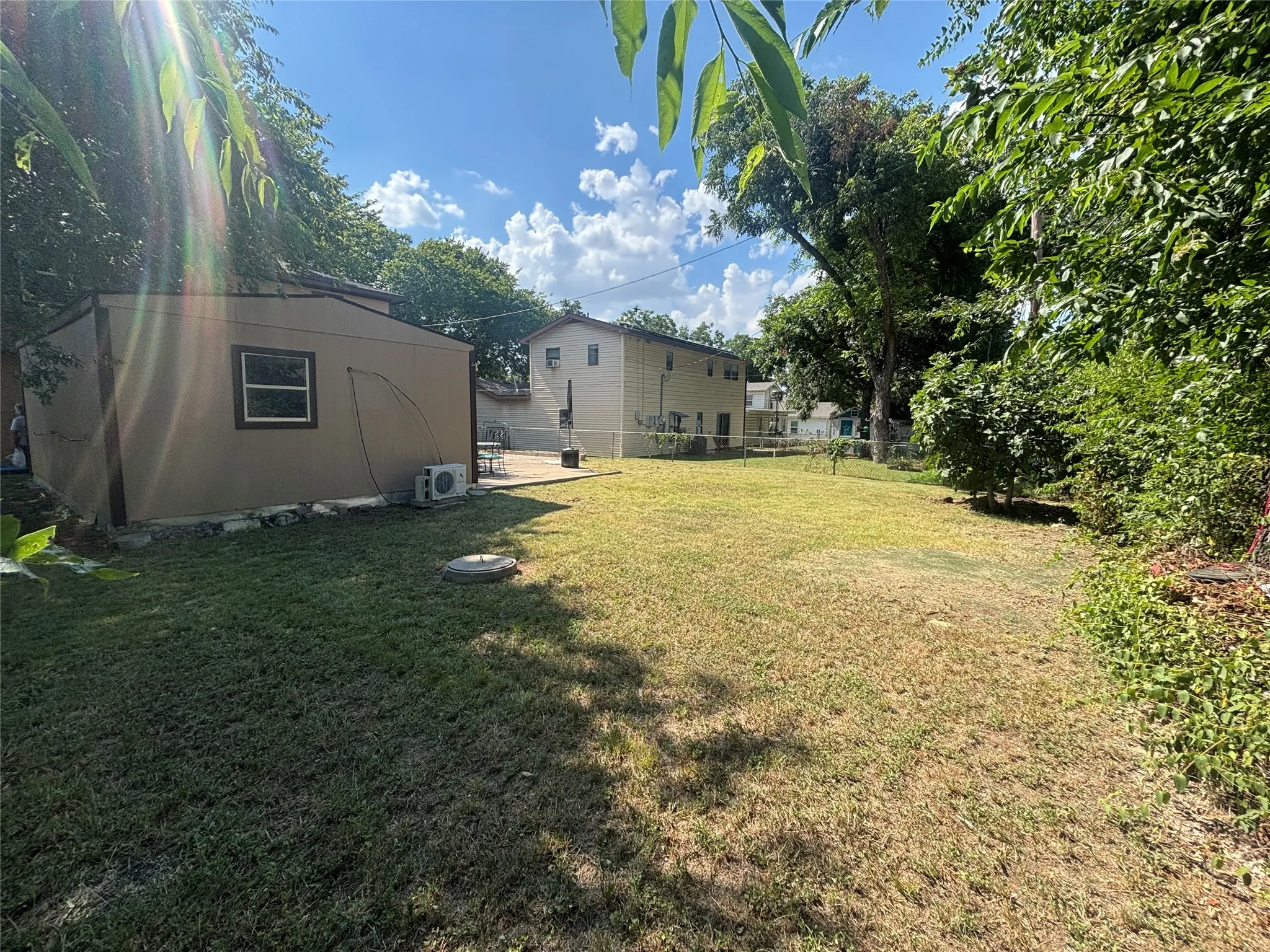 Spacious backyard with a detached shed featuring a window and two exterior units
