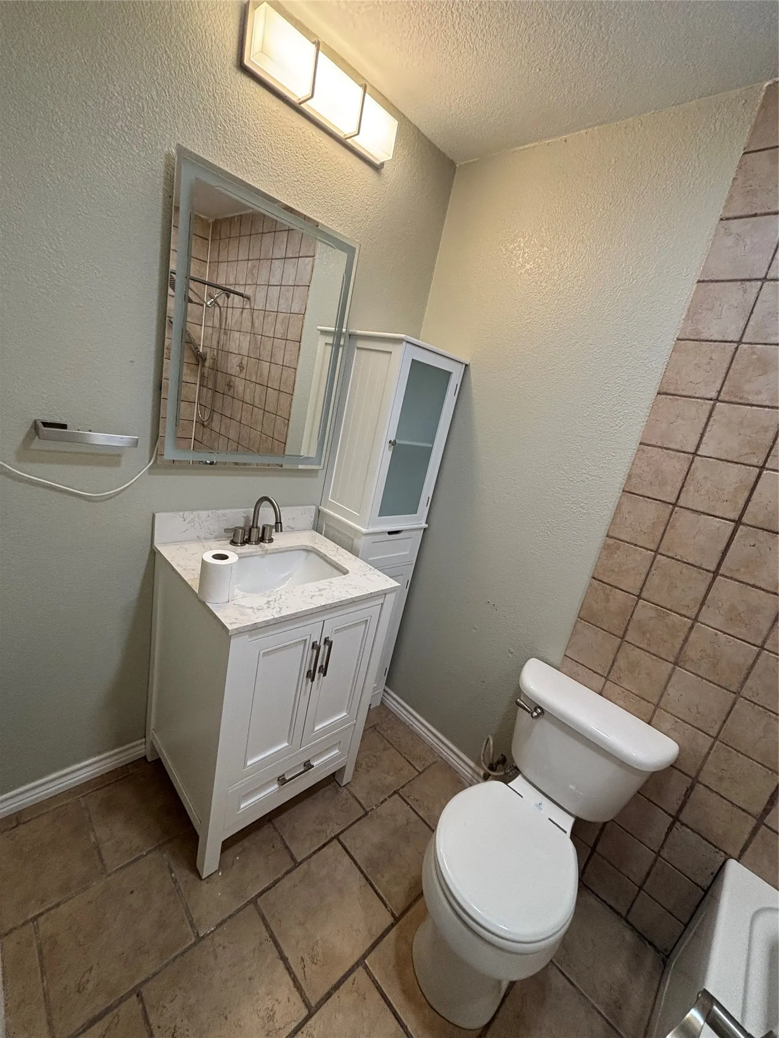 Contemporary bathroom featuring a white vanity with a rectangular sink, a stone-finish countertop, and brushed nickel hardware