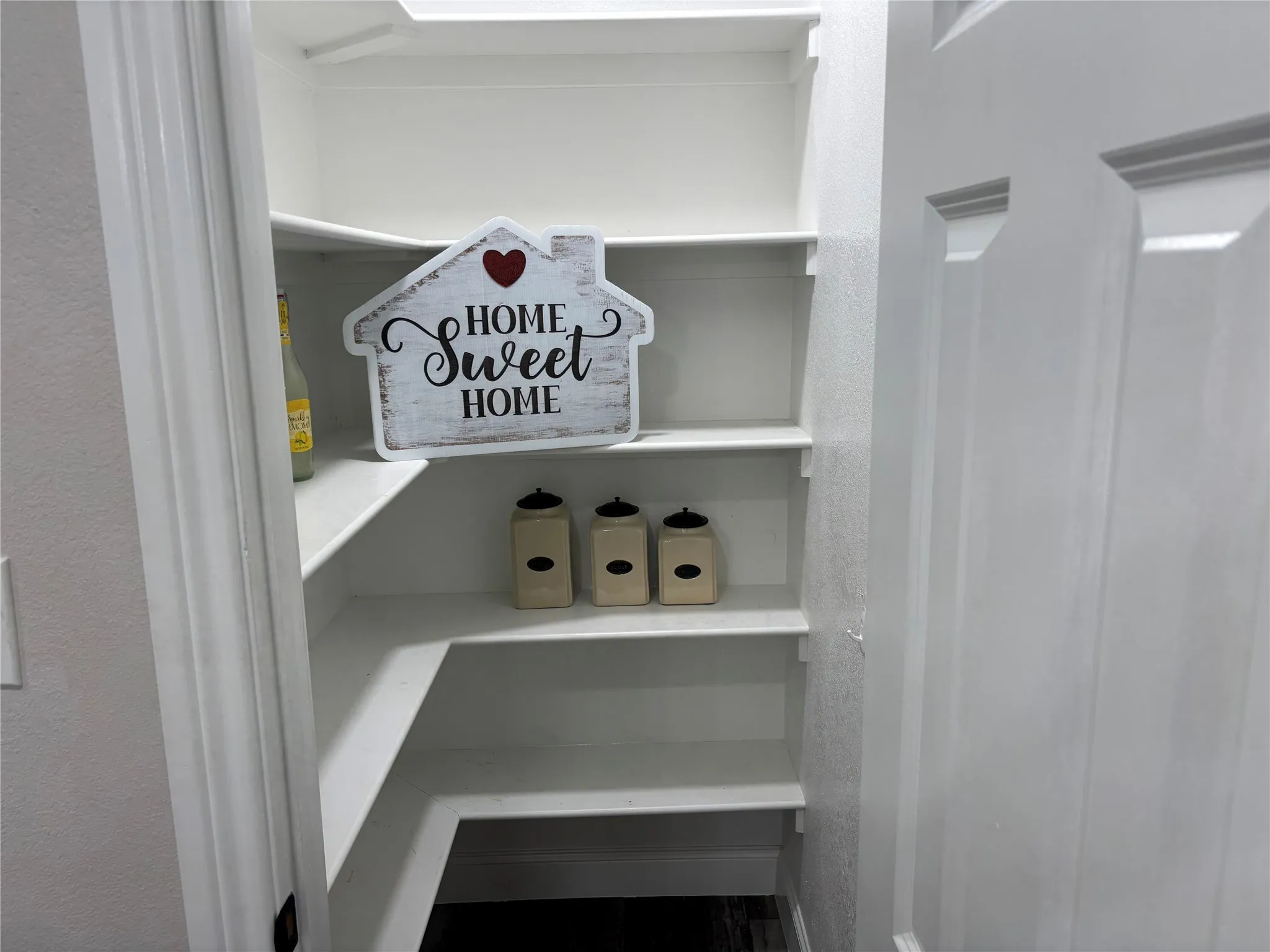 Walk-in pantry featuring white shelving and a paneled door