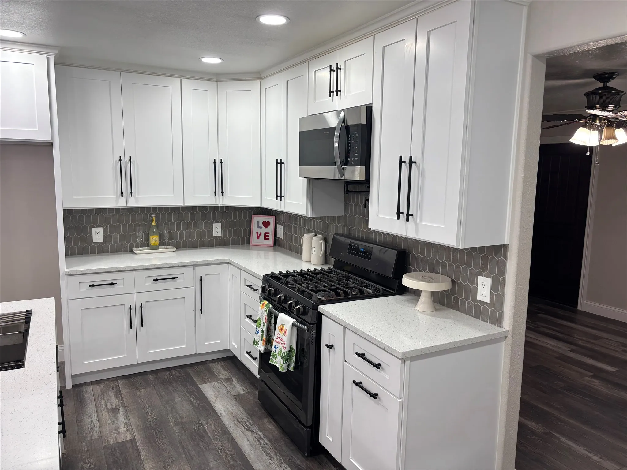 Kitchen featuring white shaker-style cabinetry with matte black hardware, white countertops, and a gray picket tile backsplash