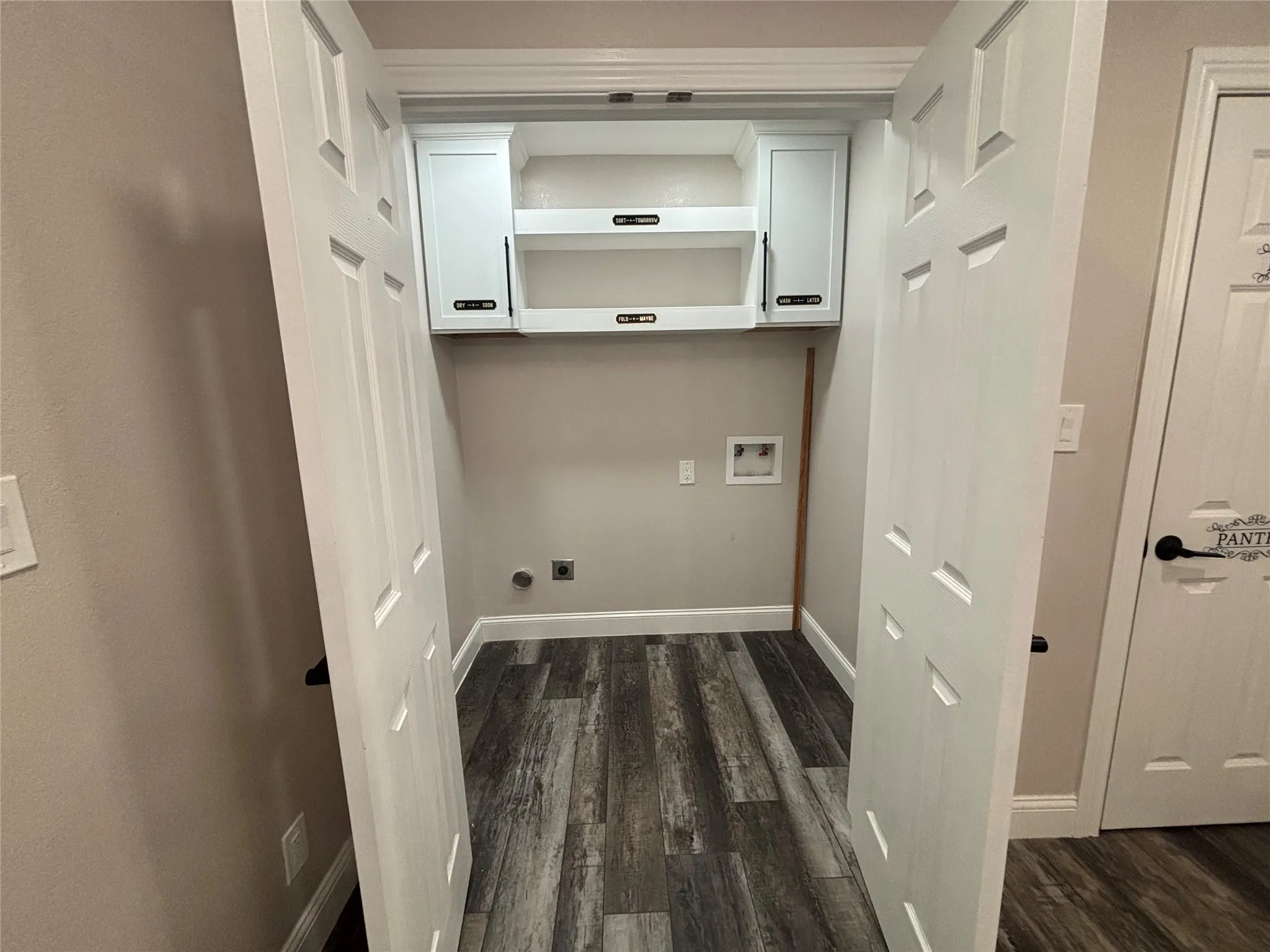Dedicated laundry area with durable wood-finish flooring, light gray wall paint, and crisp white baseboards