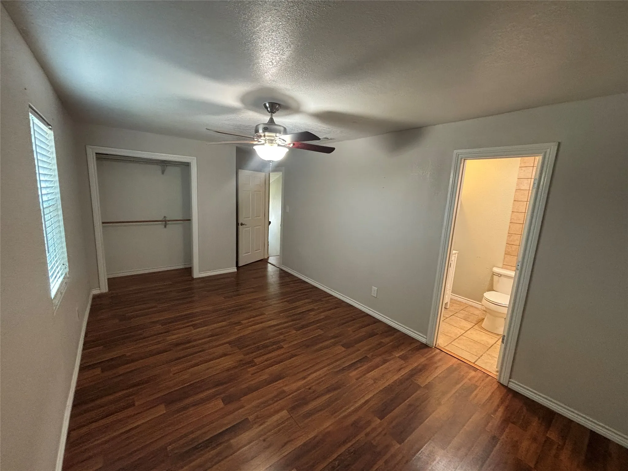 Bedroom featuring wood-finish flooring, a ceiling fan with integrated lighting, and a window with blinds