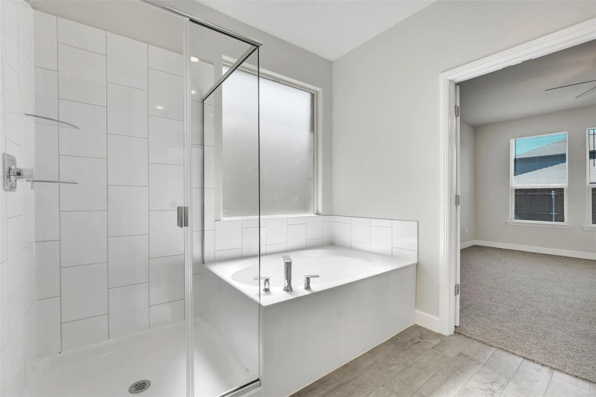 Contemporary bathroom featuring a glass-enclosed shower with white subway tile, a built-in soaking tub with chrome fixtures, and a frosted privacy window