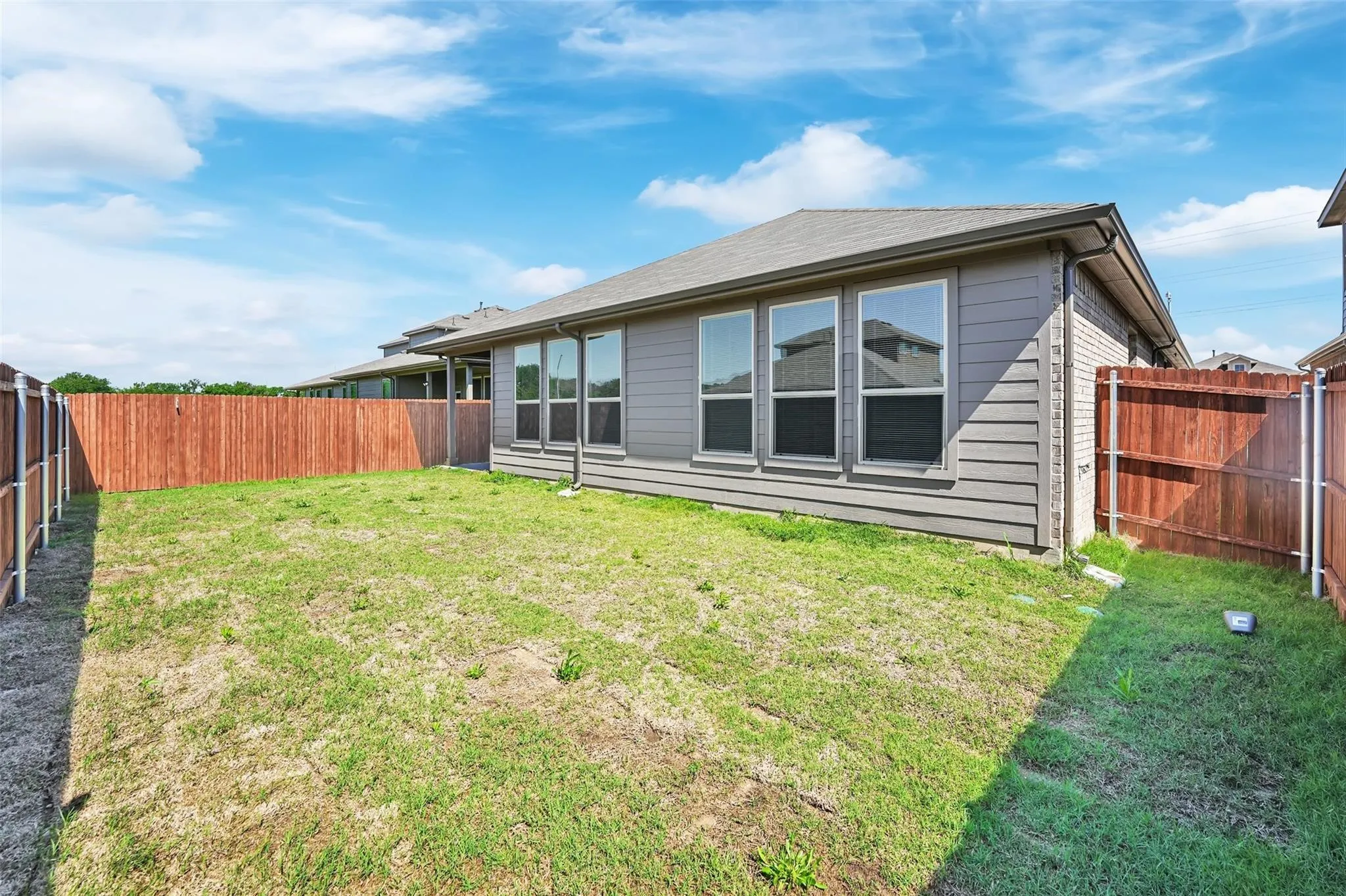 Expansive backyard with wood fencing and a gray siding exterior