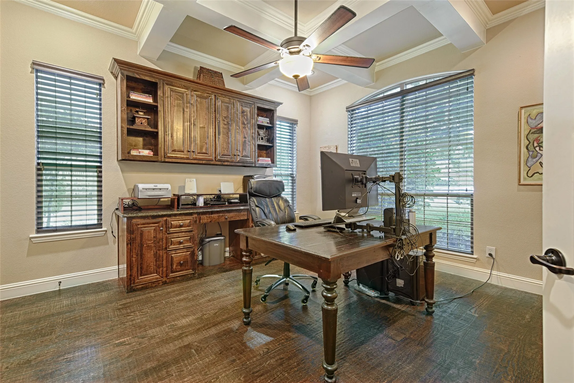 Room featuring wood-finish flooring, a built-in wood desk with integrated cabinetry, and large windows with blinds