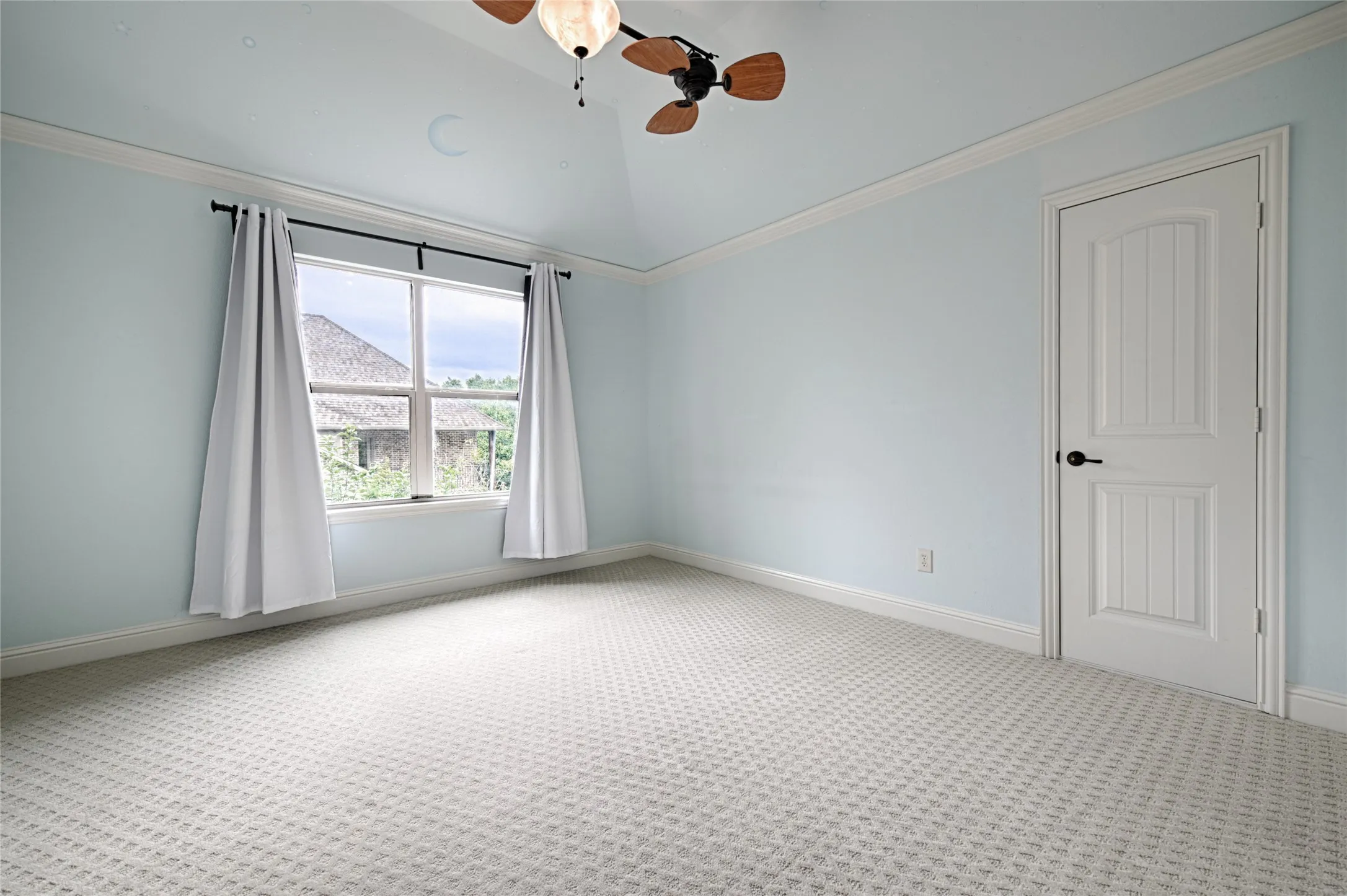 Room featuring a vaulted ceiling with ceiling fan, light blue walls, white trim, and patterned light-colored carpeting