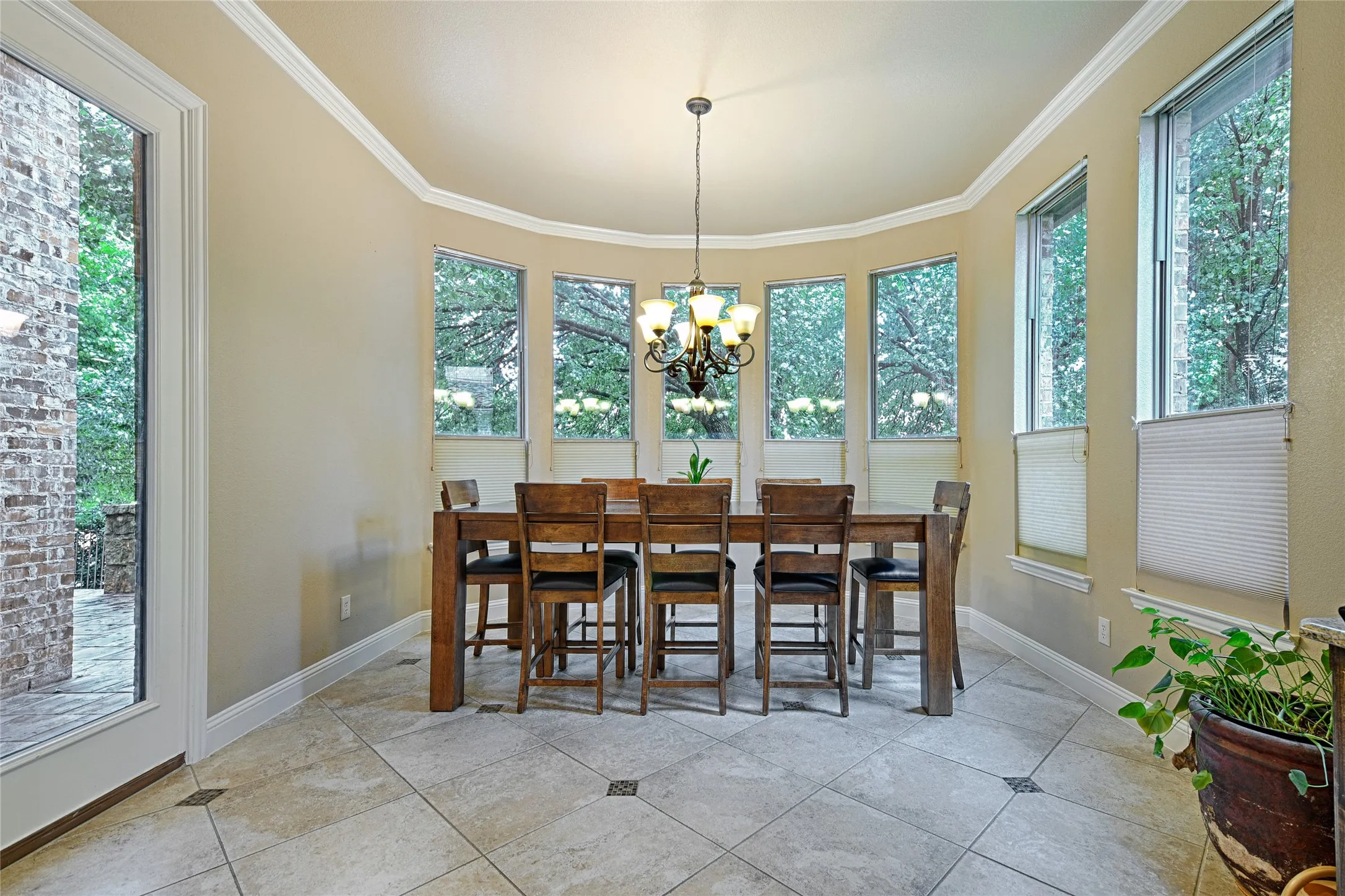 Bay window dining area featuring neutral wall tones, crown molding, and tiled flooring with decorative inlays