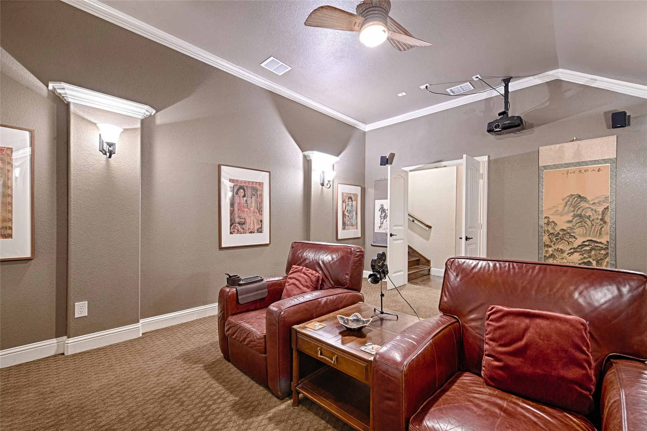 Dedicated media room featuring a ceiling-mounted projector, integrated ceiling speakers, and a ceiling fan