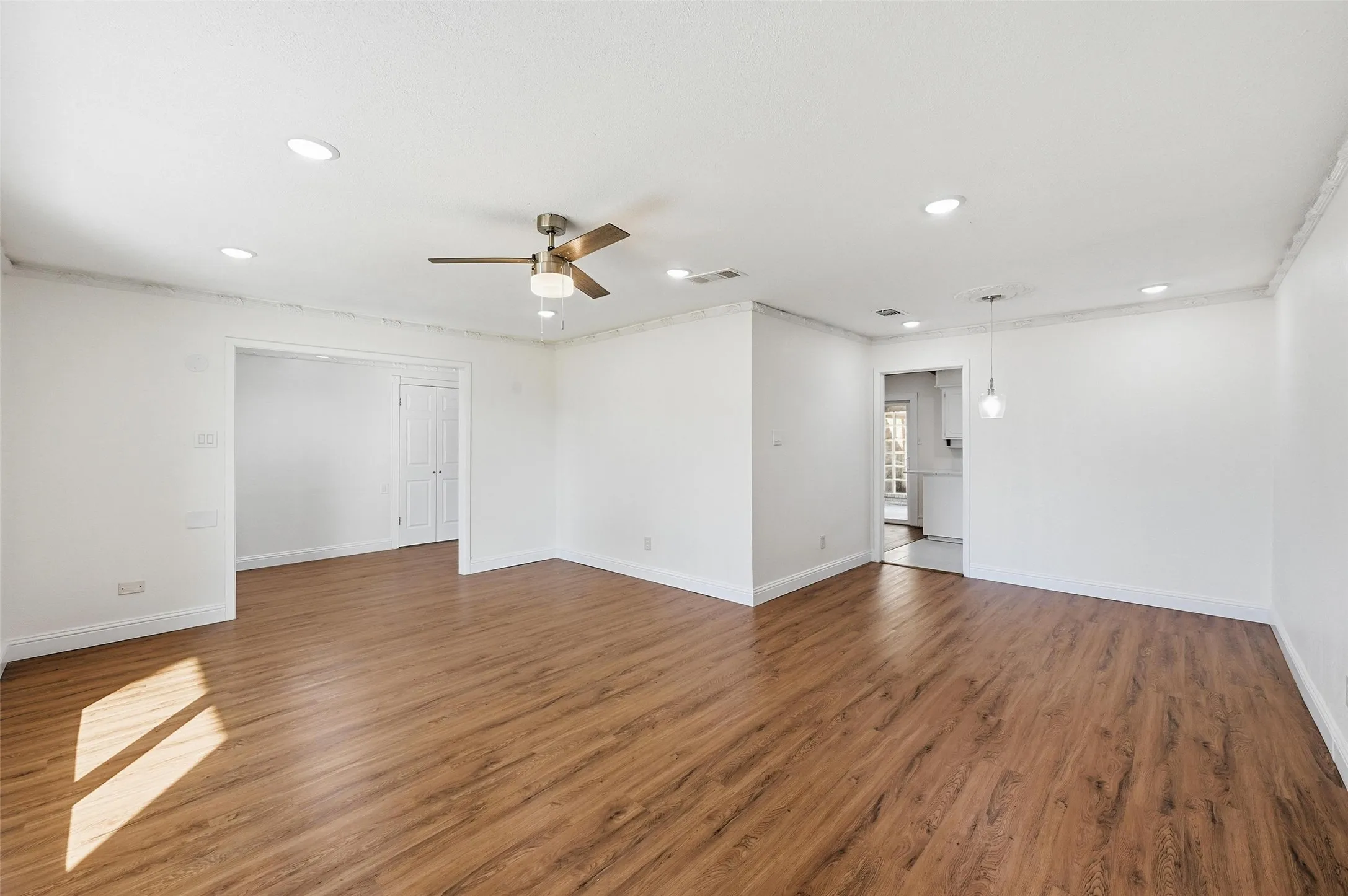 Spacious room featuring wood-finish flooring, recessed lighting, and a ceiling fan with integrated light