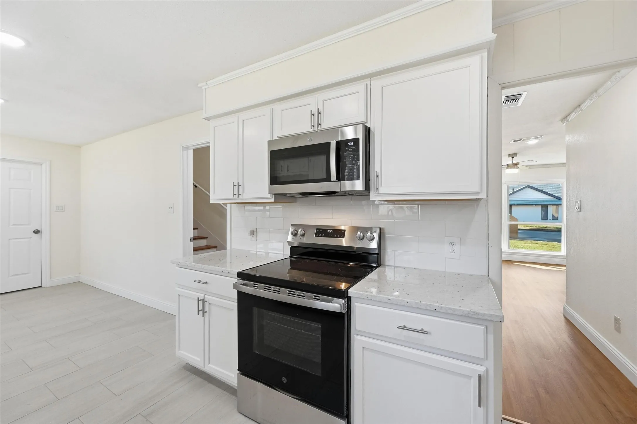 Kitchen featuring white cabinetry, stainless steel appliances, granite-look countertops, and a subway tile backsplash