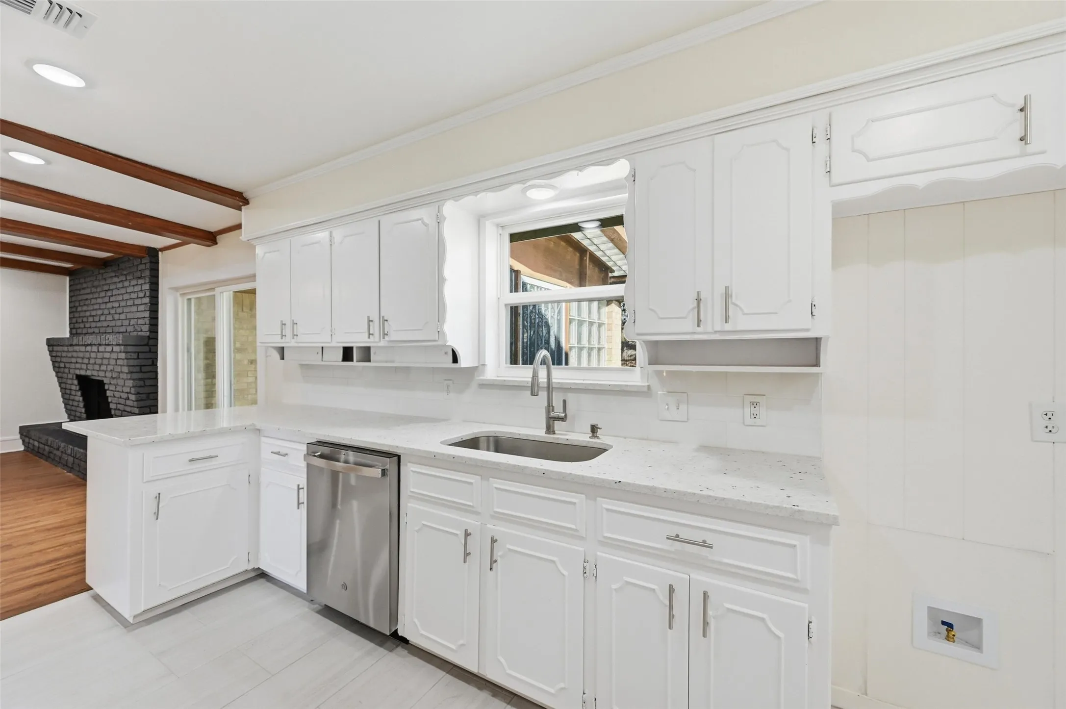 Kitchen featuring white cabinetry, light-toned countertops, a stainless steel sink with a gooseneck faucet, and stainless steel dishwasher
