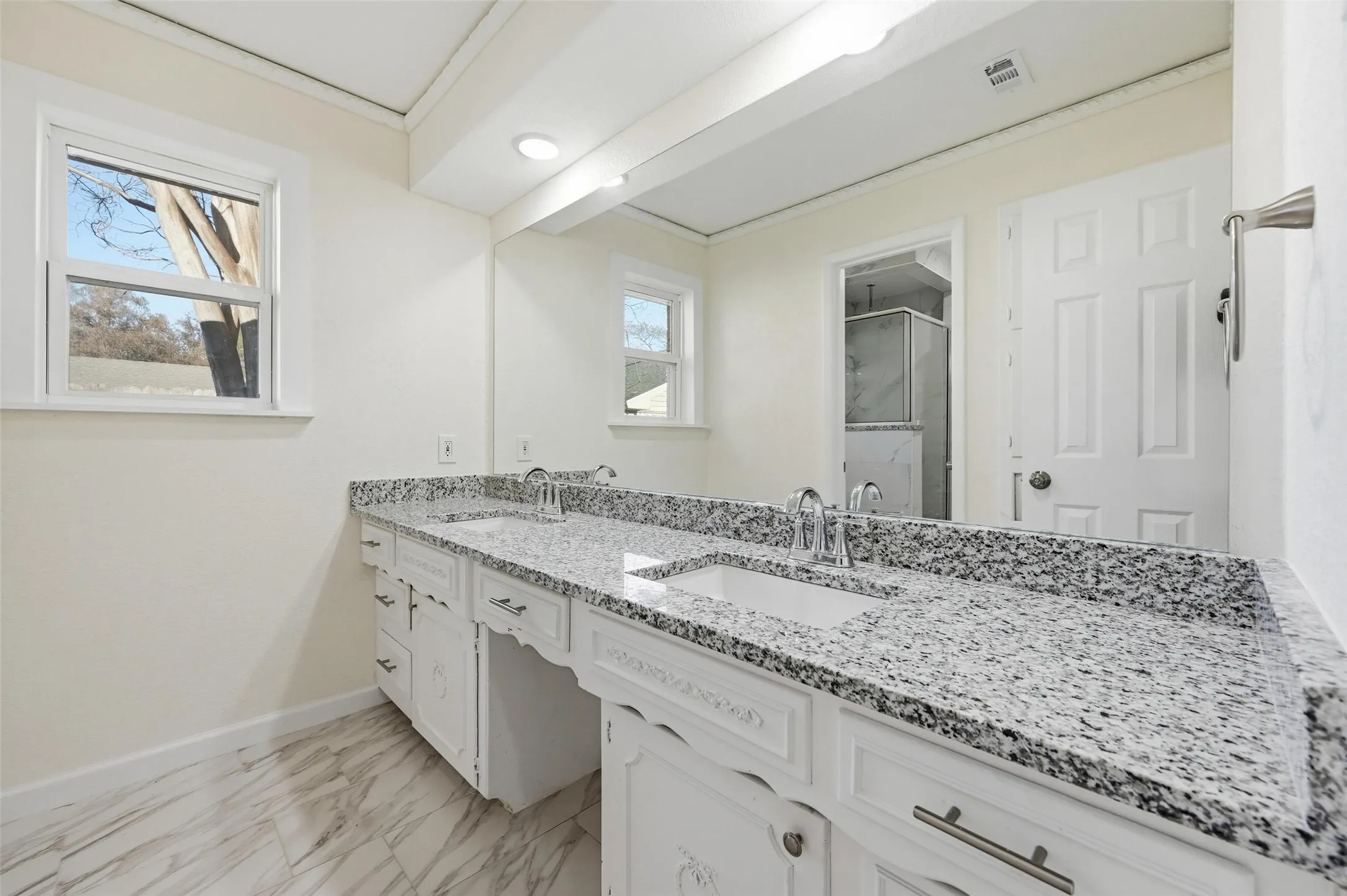 Bathroom featuring a double vanity with stone countertops, integrated sinks, white cabinetry, and brushed nickel hardware