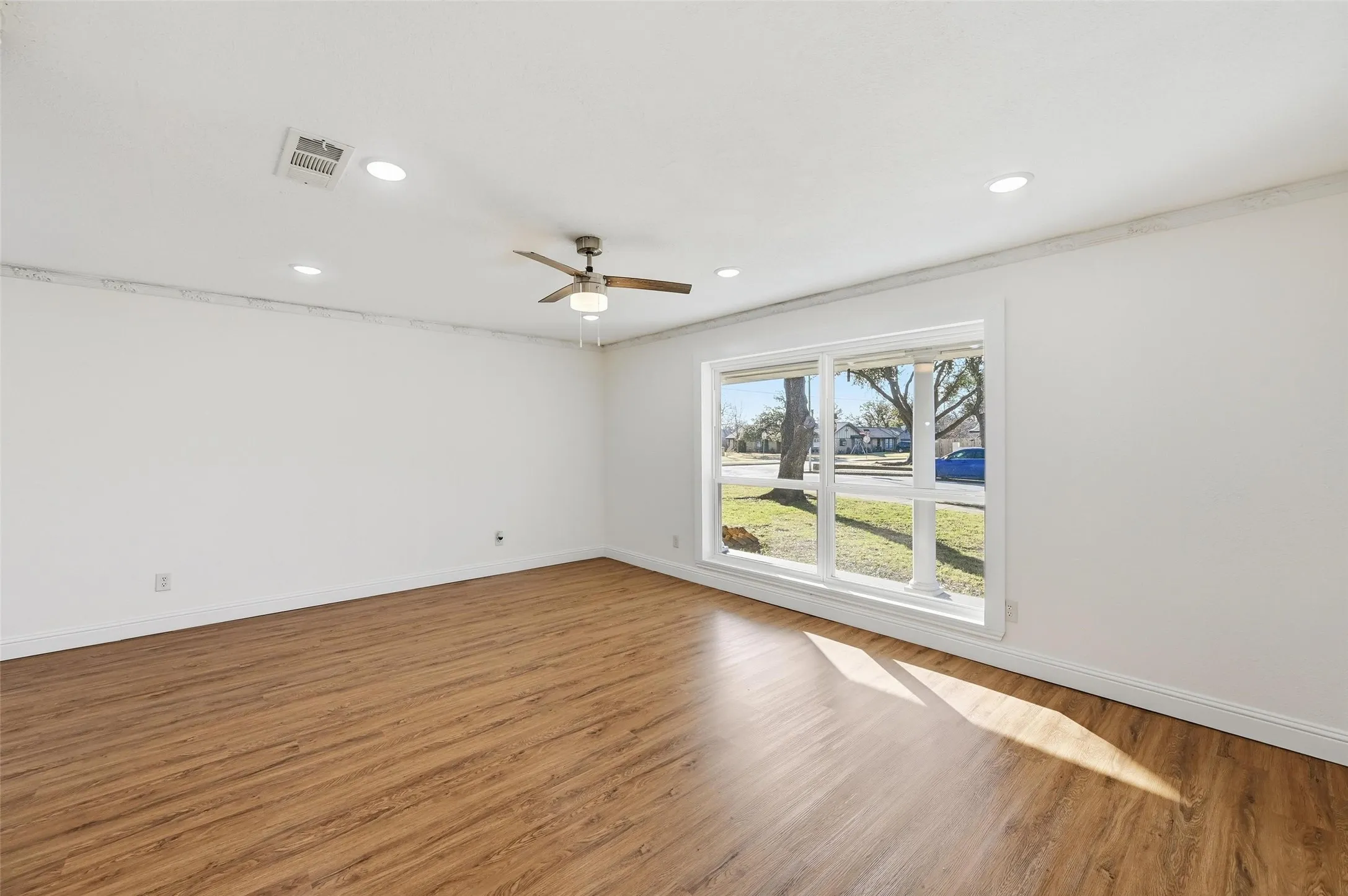 Spacious room featuring wood-finish flooring, recessed lighting, and a ceiling fan