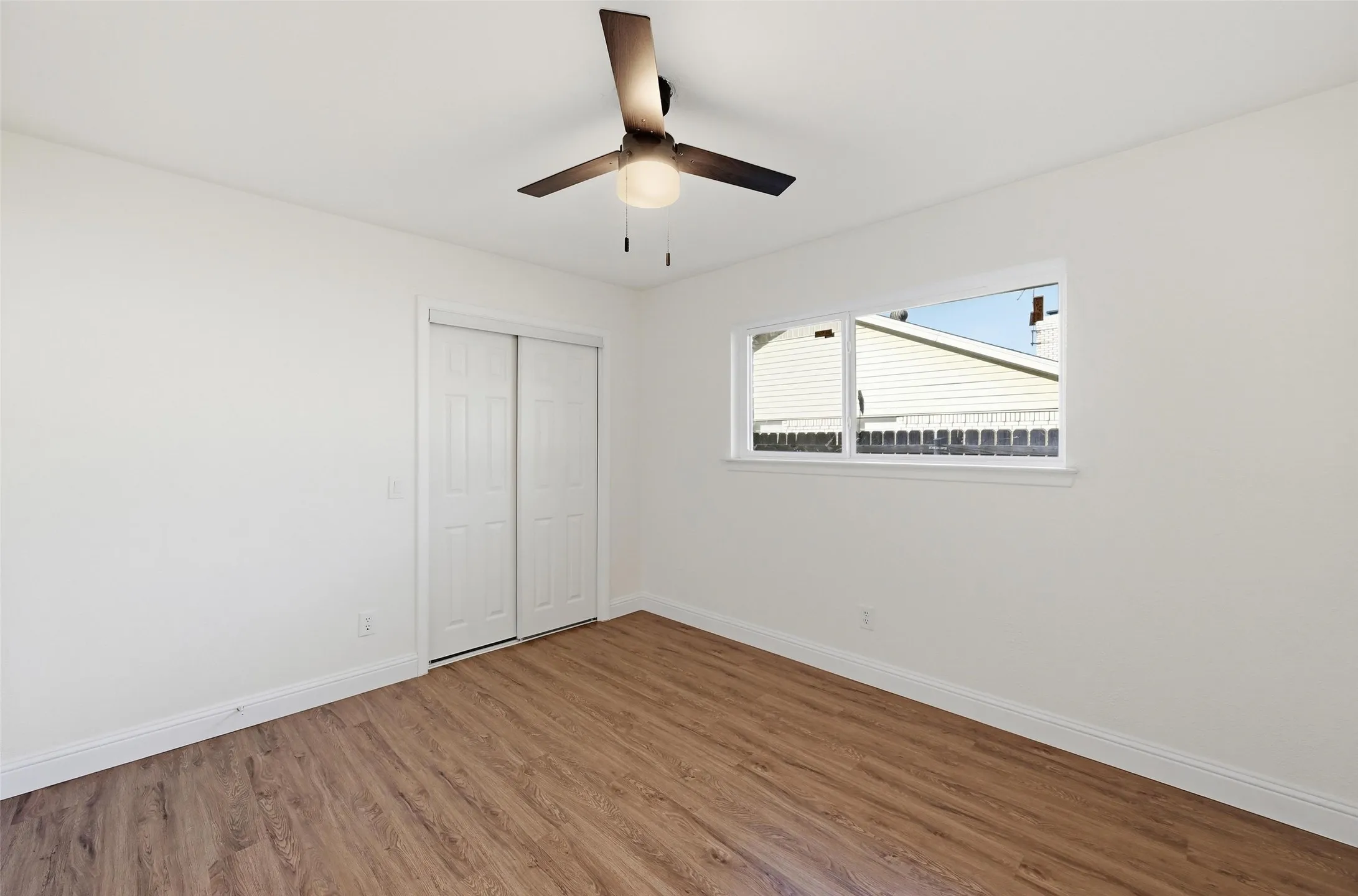 Room featuring wood-finish flooring, white baseboards, and a contemporary ceiling fan with integrated lighting