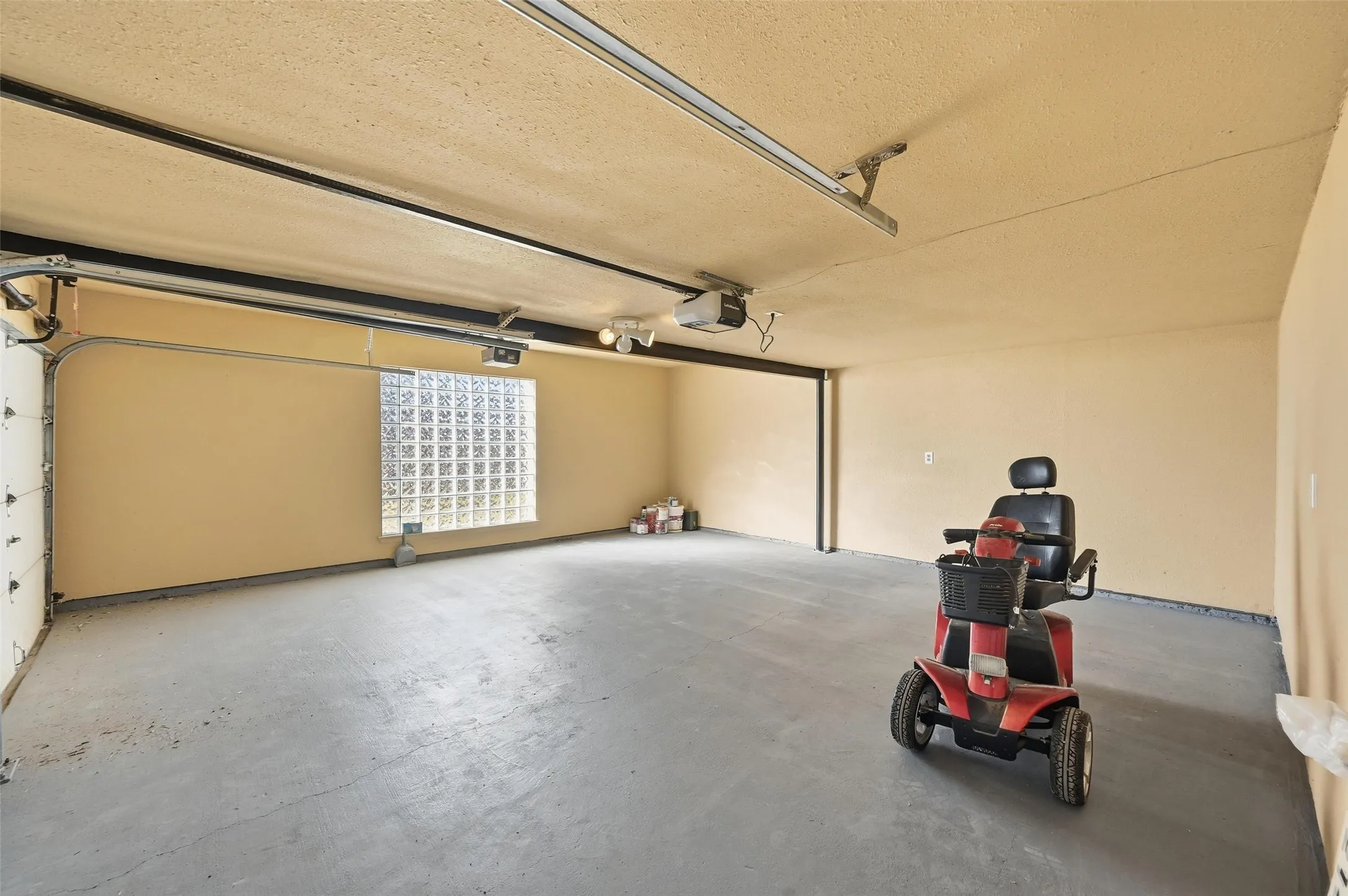 Attached garage featuring a concrete floor, painted walls, and a glass block window