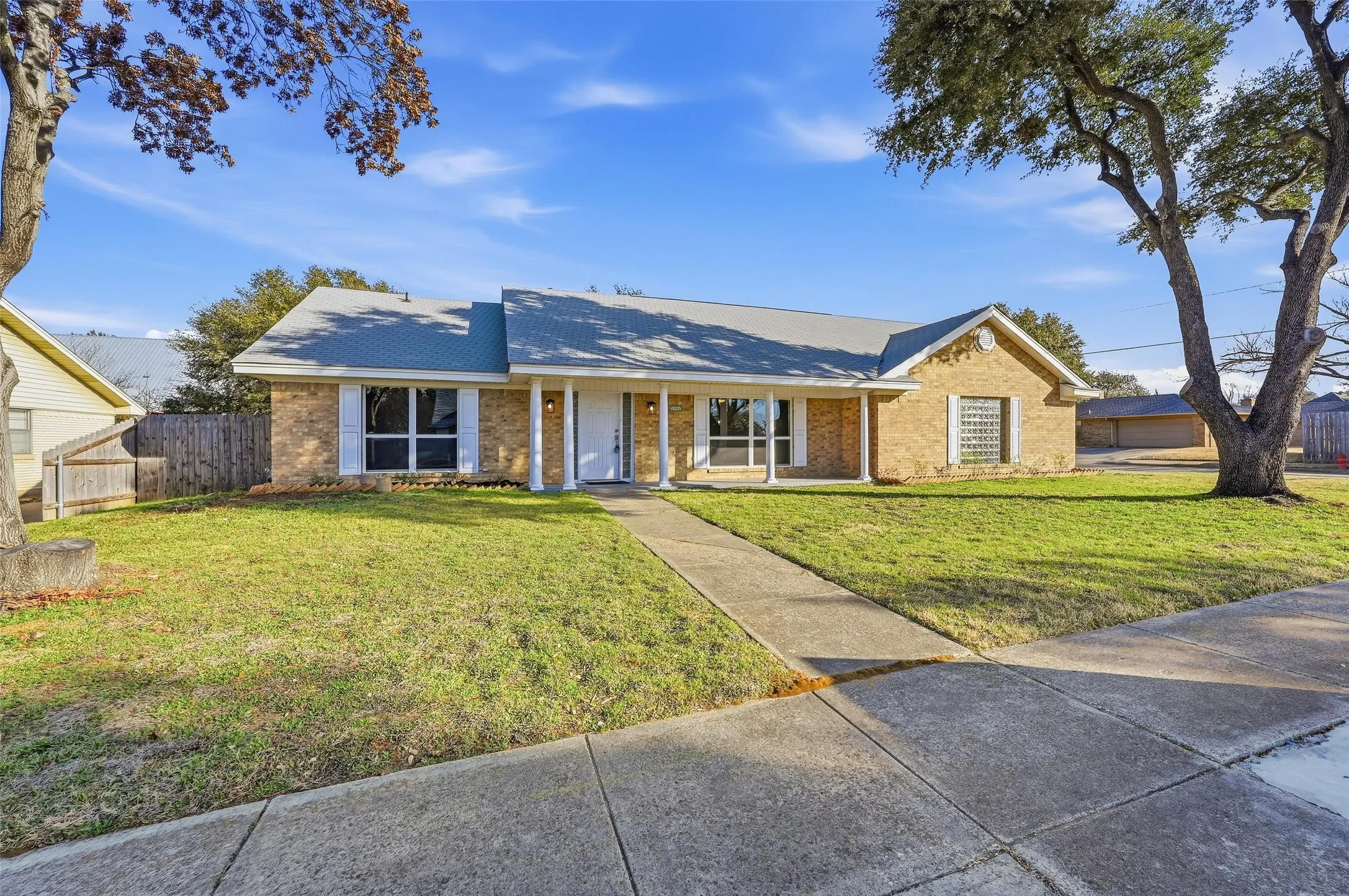 Traditional brick home featuring a covered front entry with white columns