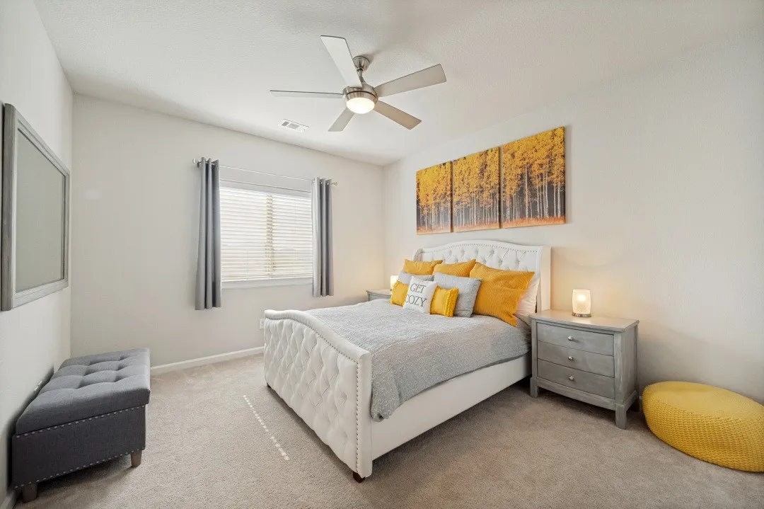 Carpeted room featuring a ceiling fan with integrated lighting, a window with blinds and drapes.