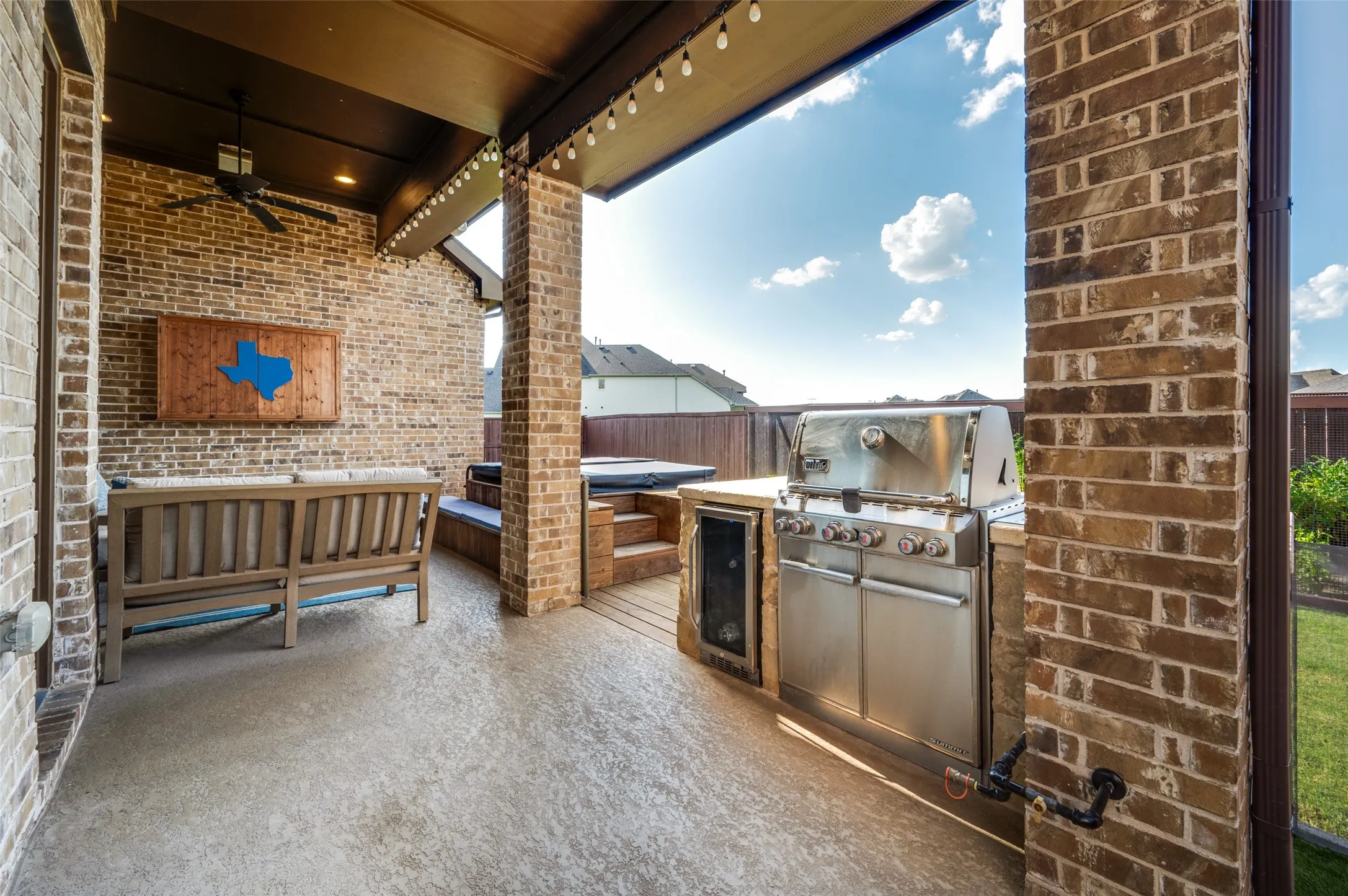 Covered patio featuring a ceiling fan, string lighting, and brick construction