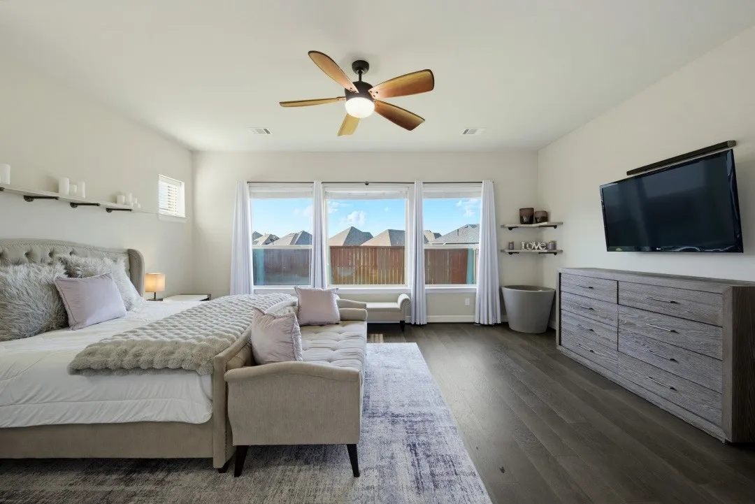 Spacious room featuring wood-finish flooring, a contemporary ceiling fan, and three large windows