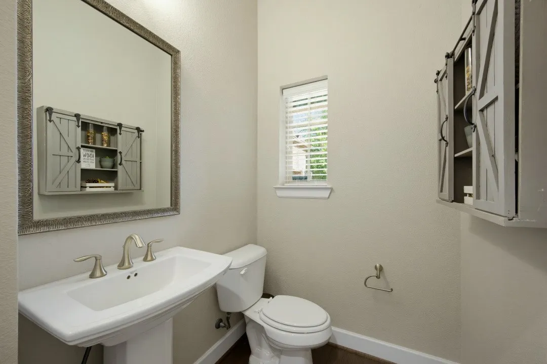 Pedestal sink with brushed nickel faucet, framed mirror, and a wall-mounted barn door style cabinet