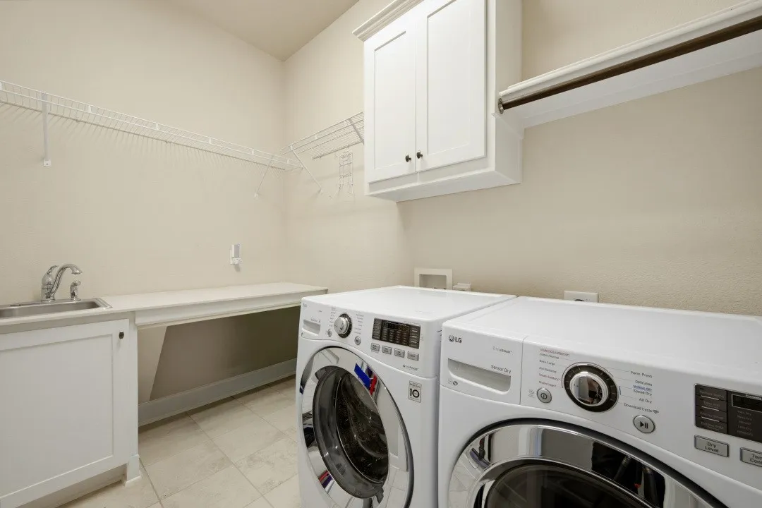 Laundry room featuring a stainless steel sink, built-in lower cabinetry, a built-in folding counter, upper cabinetry, and wire shelving