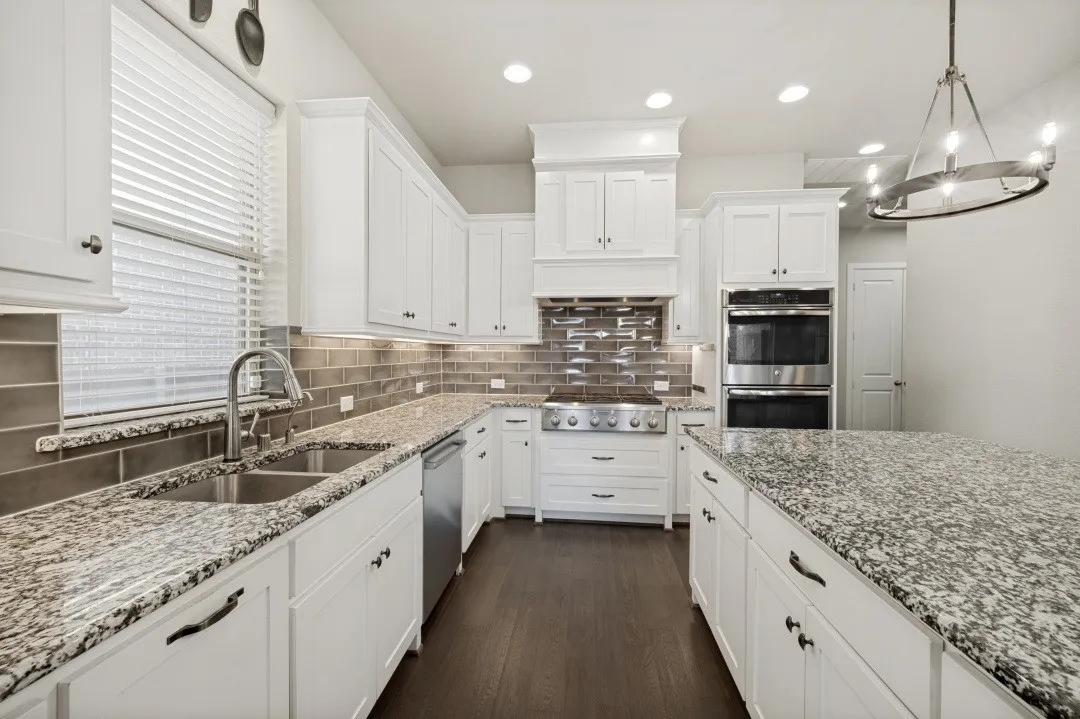 Gourmet kitchen featuring white cabinetry, granite countertops, stainless steel appliances, a tiled backsplash, and recessed lighting
