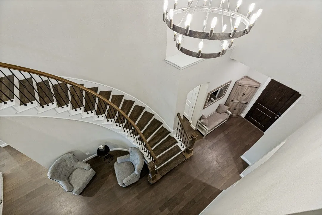 Curved hardwood staircase with white risers and dark wood treads, featuring black metal balusters and a wood handrail