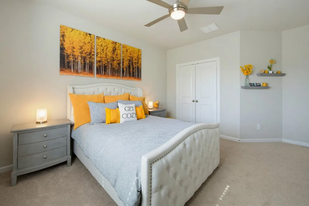 Carpeted bedroom featuring a ceiling fan with integrated lighting, double-door closet, and floating wall shelves