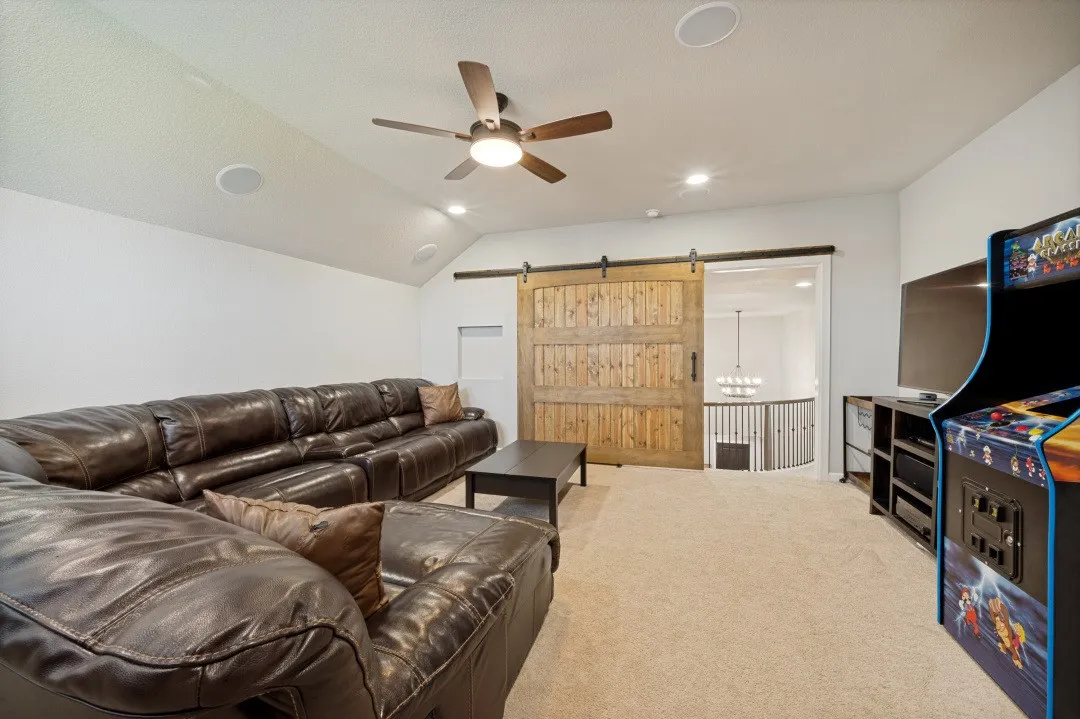 Spacious media/game room featuring a vaulted ceiling with a ceiling fan, recessed lighting, and built-in ceiling speakers