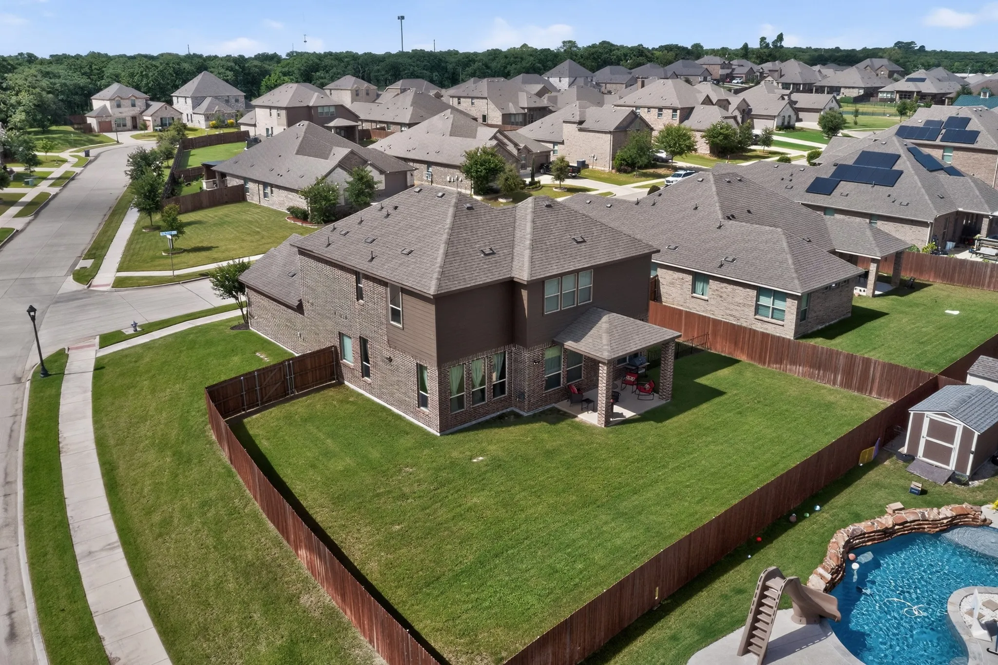 Two-story home featuring brick and siding exterior, a gabled roof, and a covered back patio