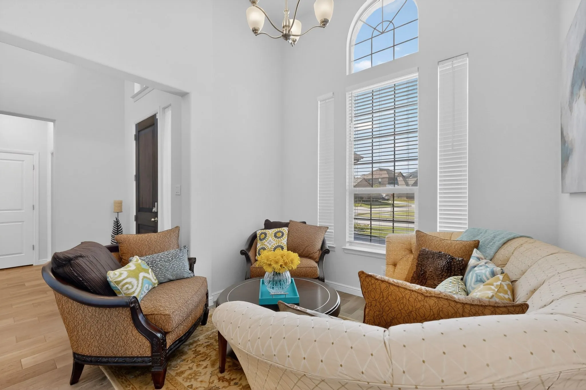Sun-filled living space featuring high ceilings, a prominent arched window, and additional windows with blinds