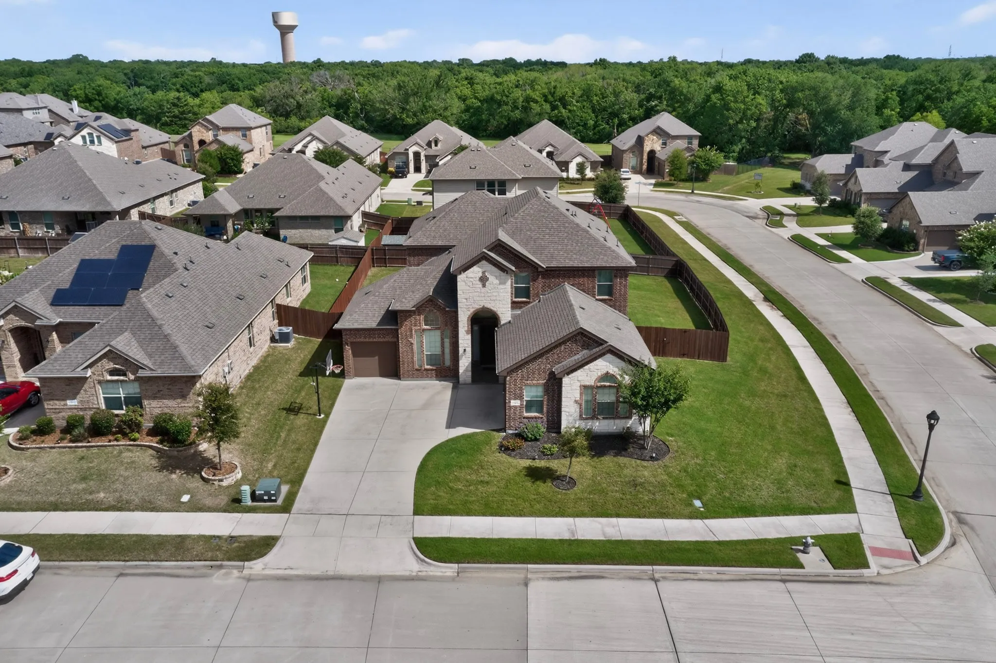 Brick and stone facade home featuring a two-car garage, a concrete driveway, and a manicured front lawn