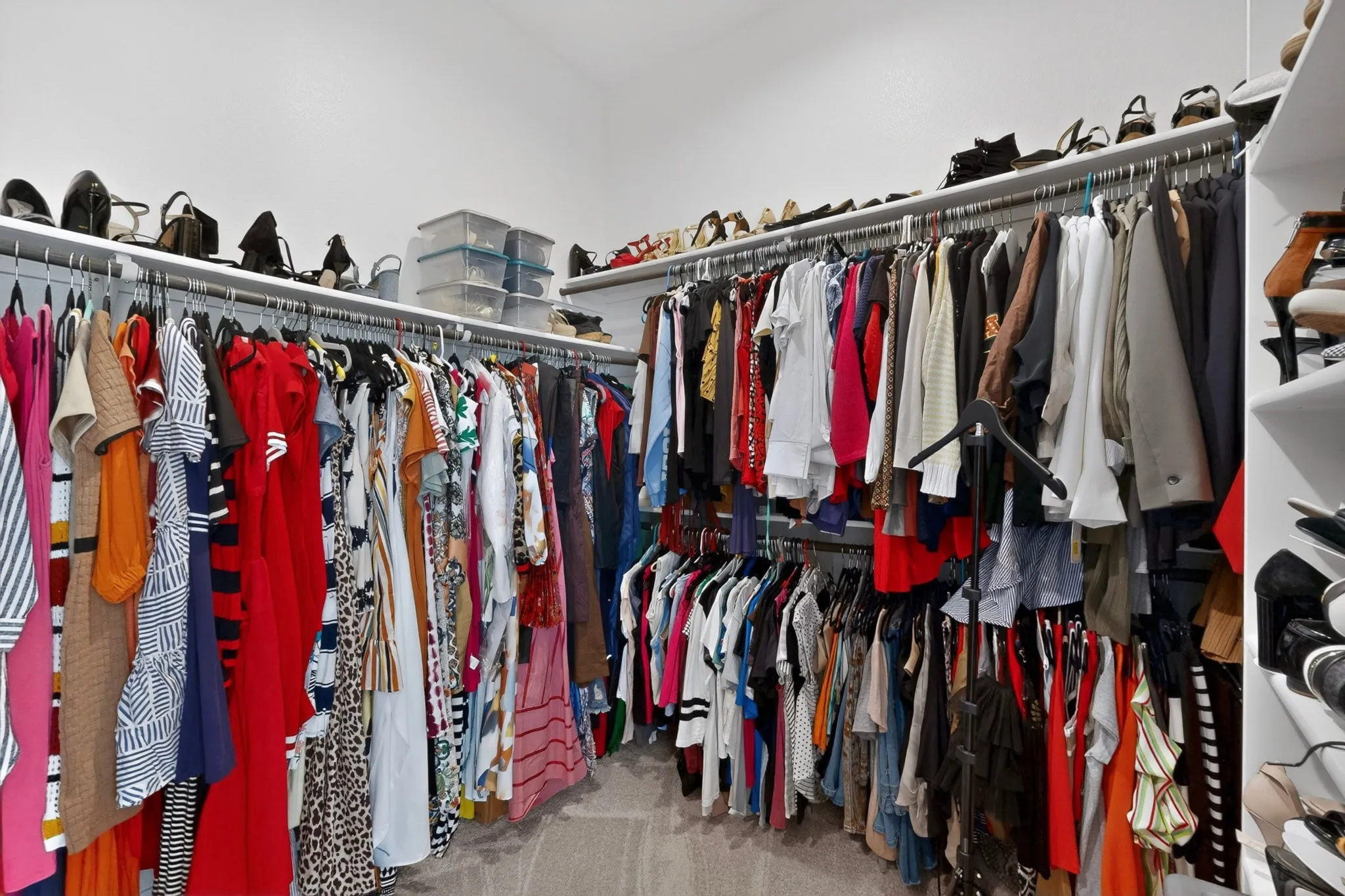 Expansive walk-in closet featuring multiple hanging rods, overhead shelving, and built-in shoe storage