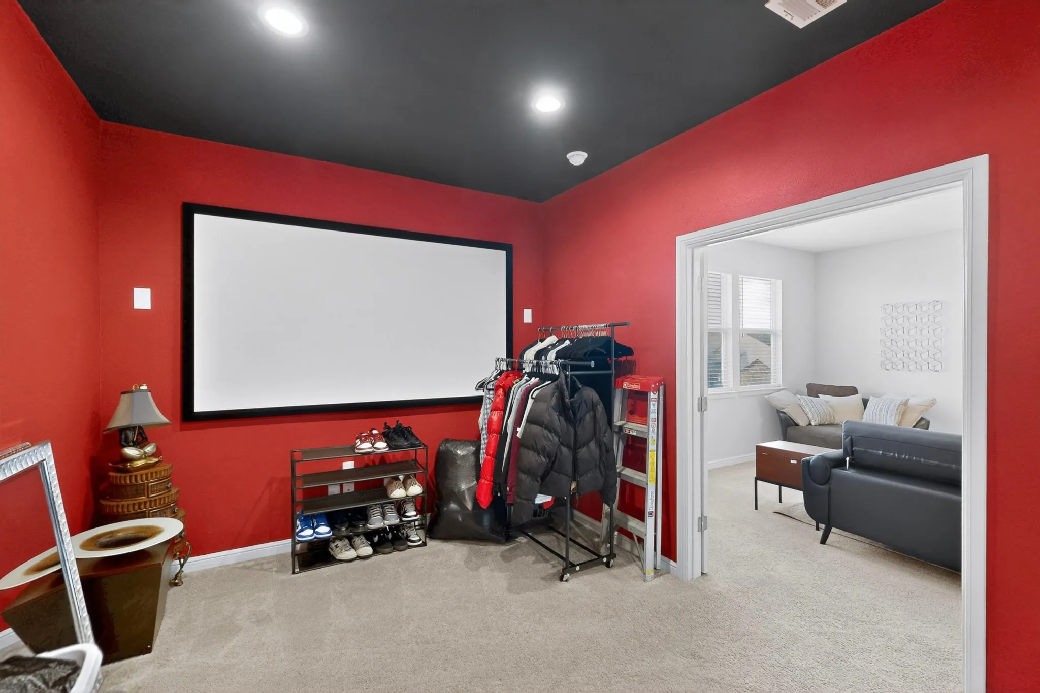 Dedicated media room featuring a large projection screen, recessed lighting, and soft carpet flooring
