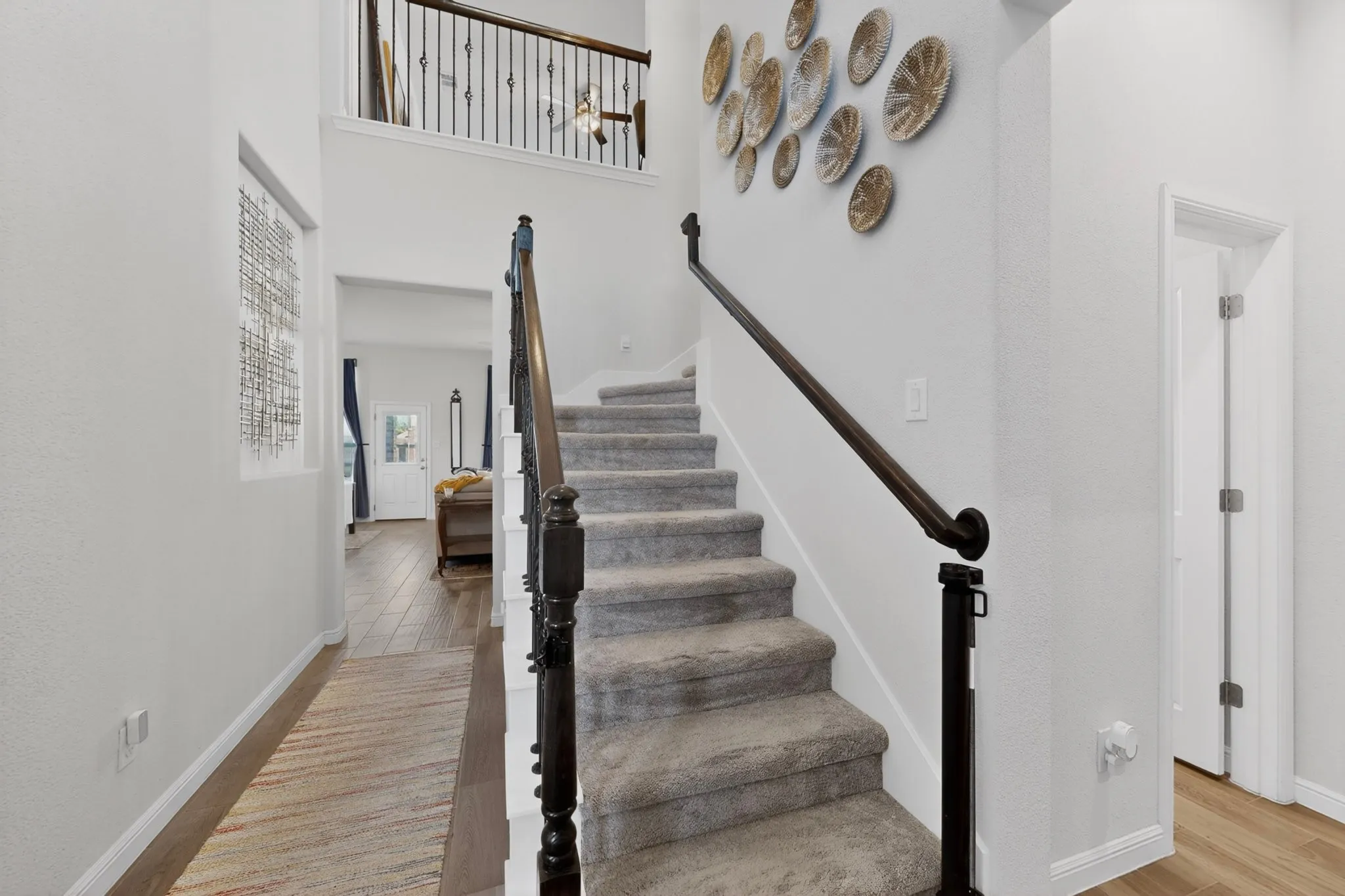 Two-story foyer featuring a carpeted staircase with dark wood newel posts and handrail, iron balusters, and wood-finish flooring