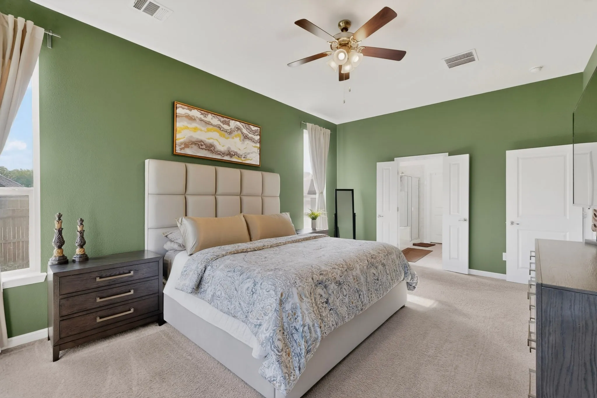 Bedroom featuring light carpet flooring, green wall paint, and a ceiling fan with integrated lighting