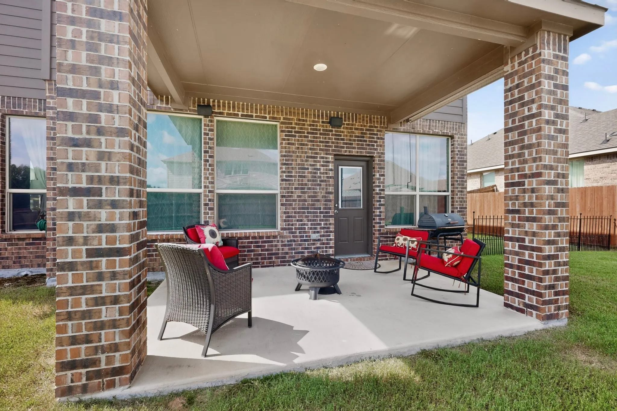 Covered patio featuring a concrete slab, brick support columns, and multiple large windows