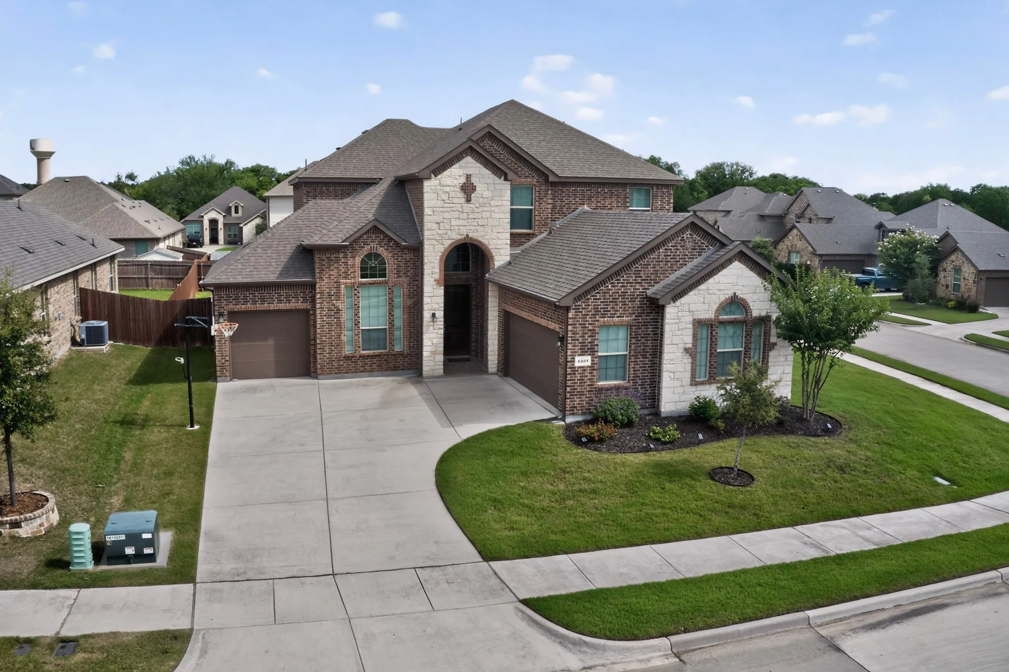 Two-story brick and stone facade residence featuring a front entry, arched window accents, and an attached two-car garage