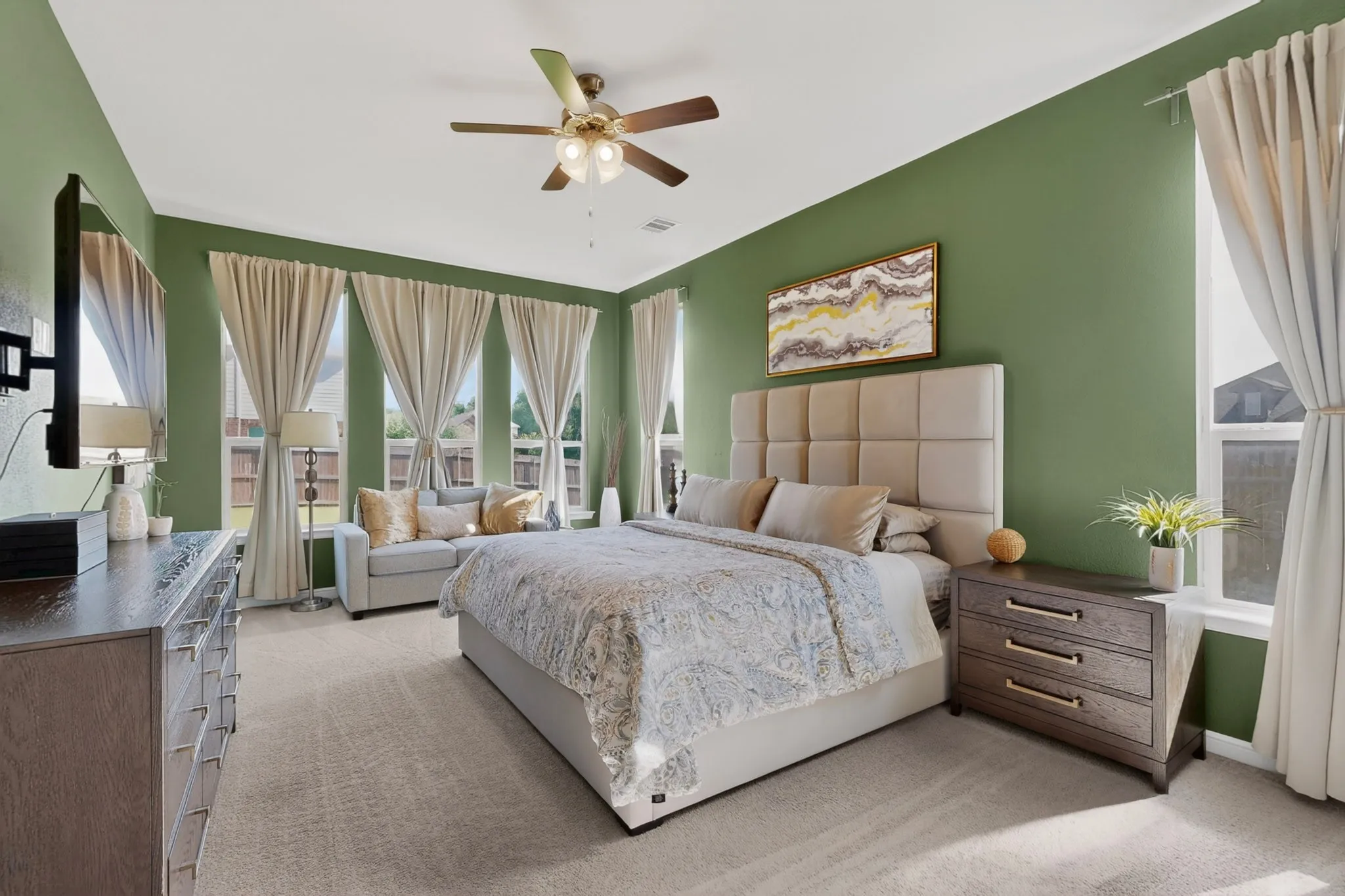 Carpeted bedroom with green accent walls and a ceiling fan