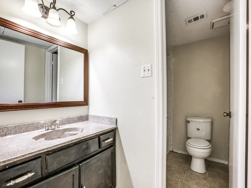 Bathroom featuring a textured ceiling, toilet, vanity, and tile patterned floors